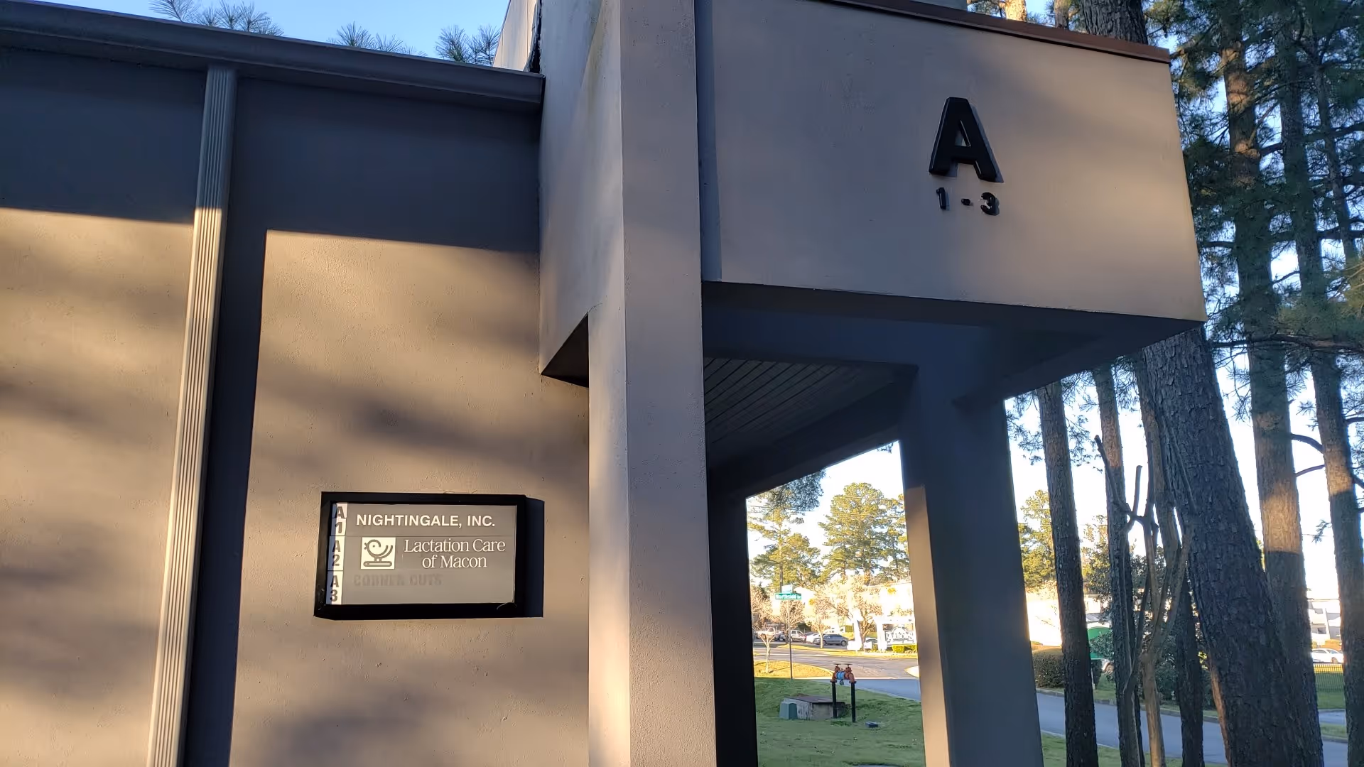Exterior view of a modern building entrance with a tall pillar and Nightingale sign