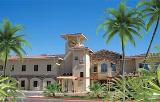 Exterior view of Paradise Village senior living facility with palm trees and blue sky