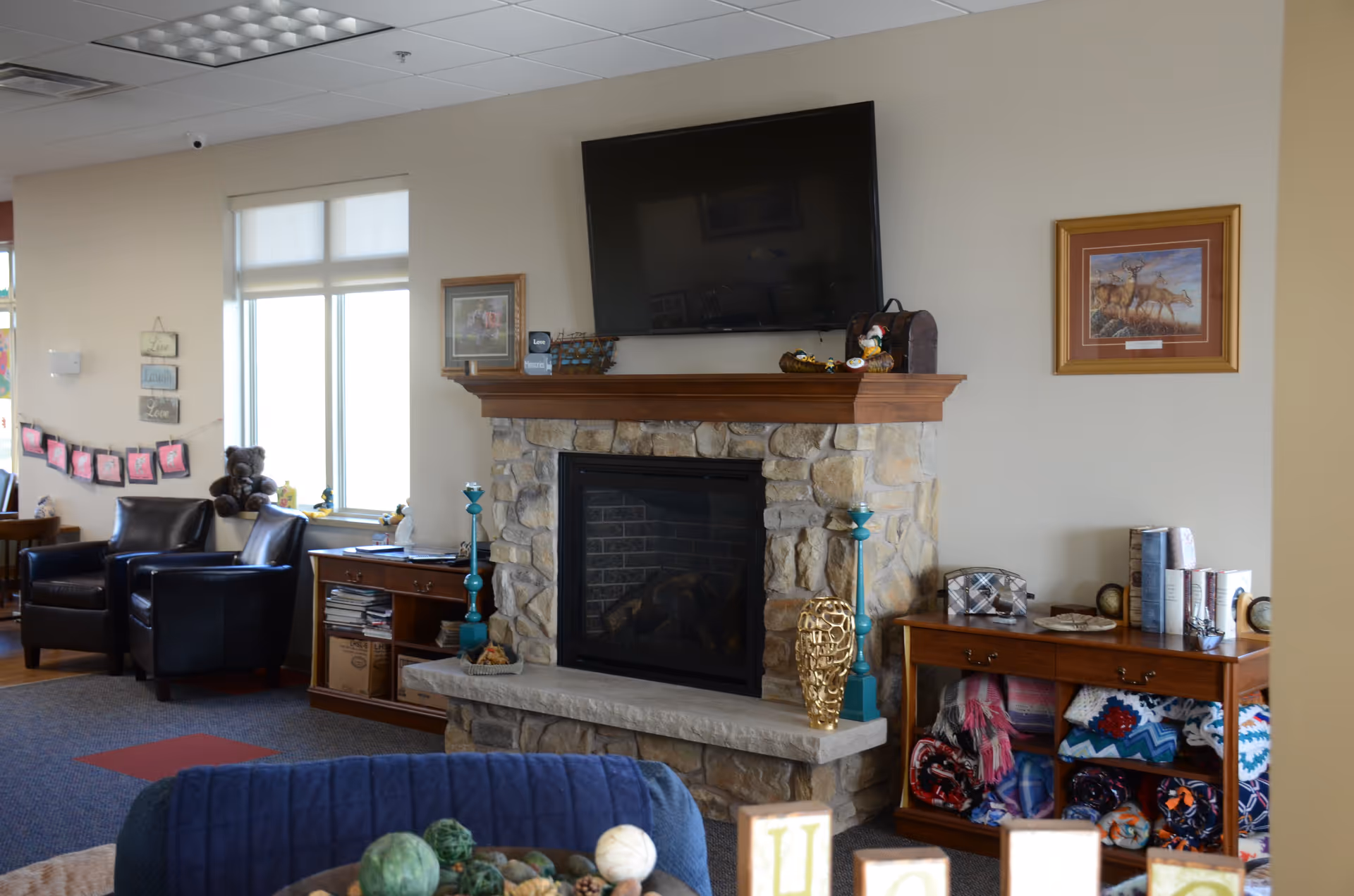 Cozy common living room with a stone fireplace, mounted TV, and seating area.
