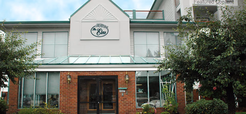Exterior view of a two-story brick facility with glass doors and trees.