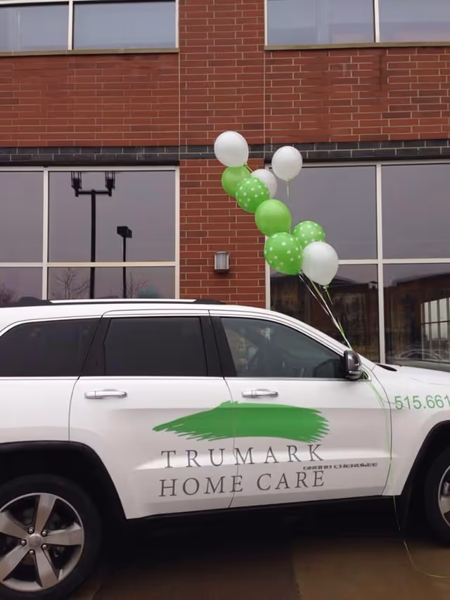 Front exterior of a brick building with a branded Trumark Home Care vehicle and balloons.