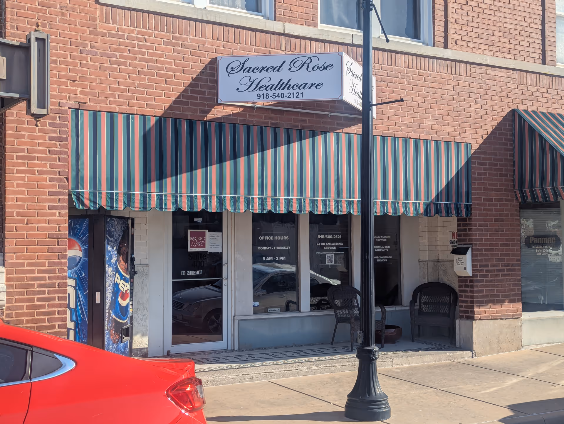 Brick storefront with striped awnings and seating outside Sacred Rose Healthcare.
