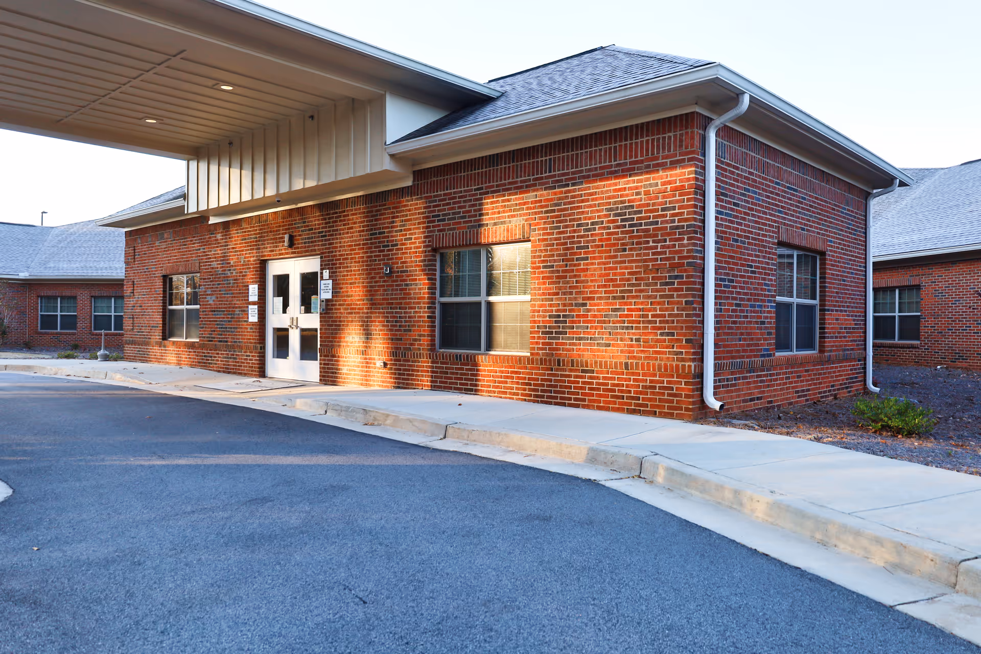 Brick hospice building exterior with a covered entrance and curved driveway.