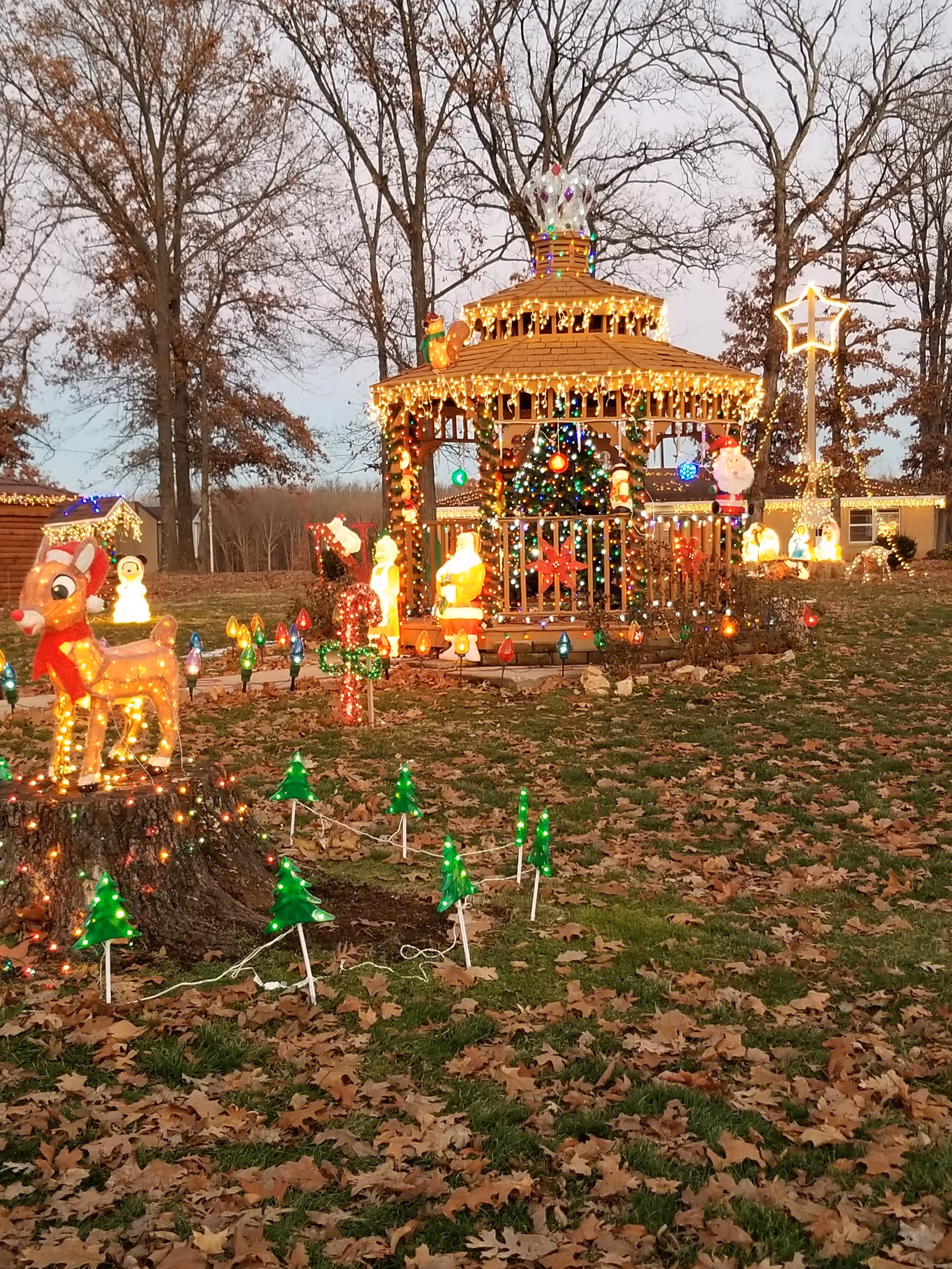 Festive outdoor gazebo lit with holiday decorations and illuminated yard displays.