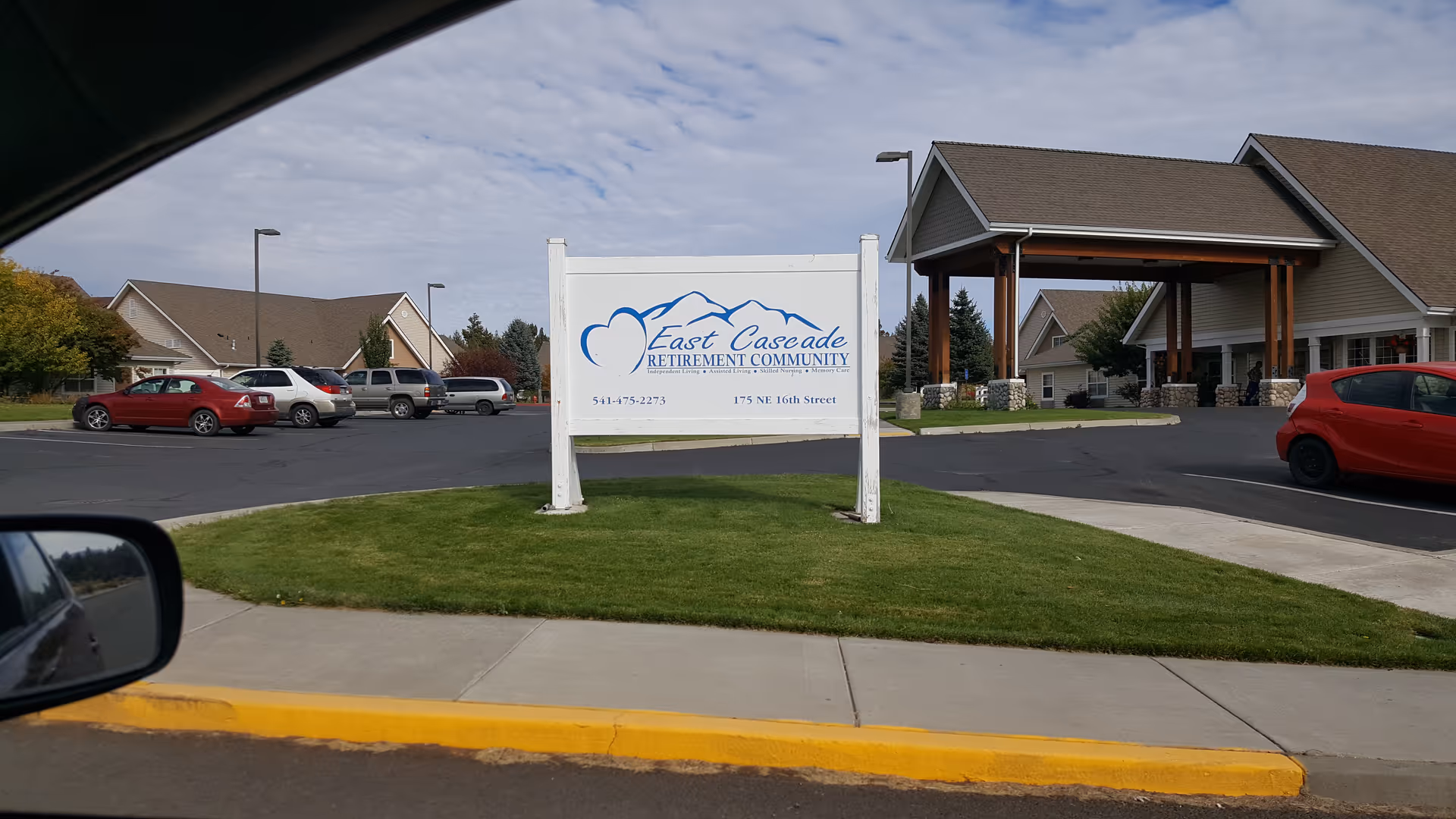 Exterior view of East Cascade Retirement Community with sign and parked cars.