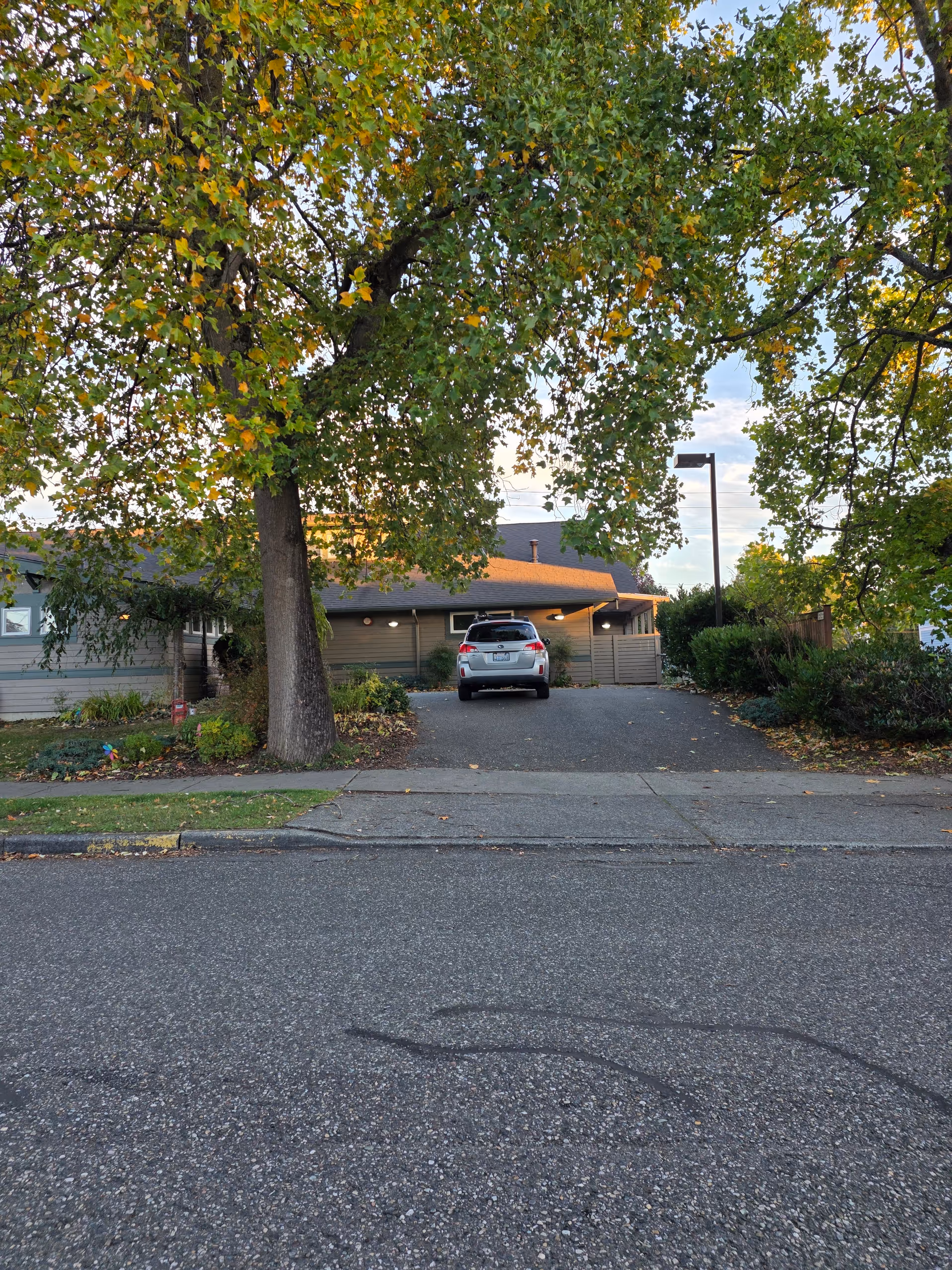 Exterior view of a single-story senior living facility with a driveway and parked car.