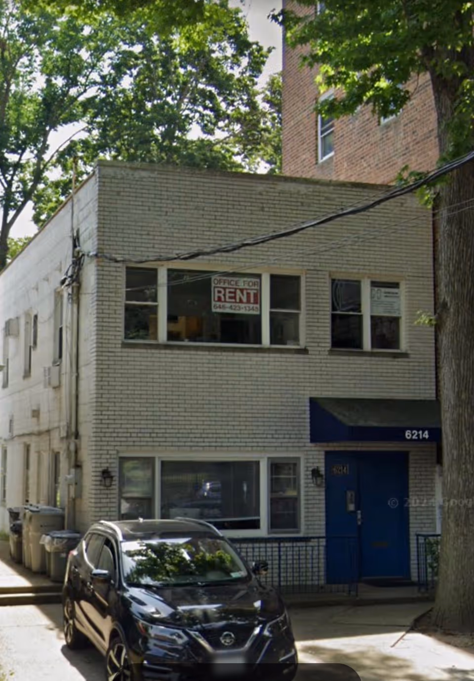 Two-story brick building with a blue door, parked car, and 'Office for Rent' sign.