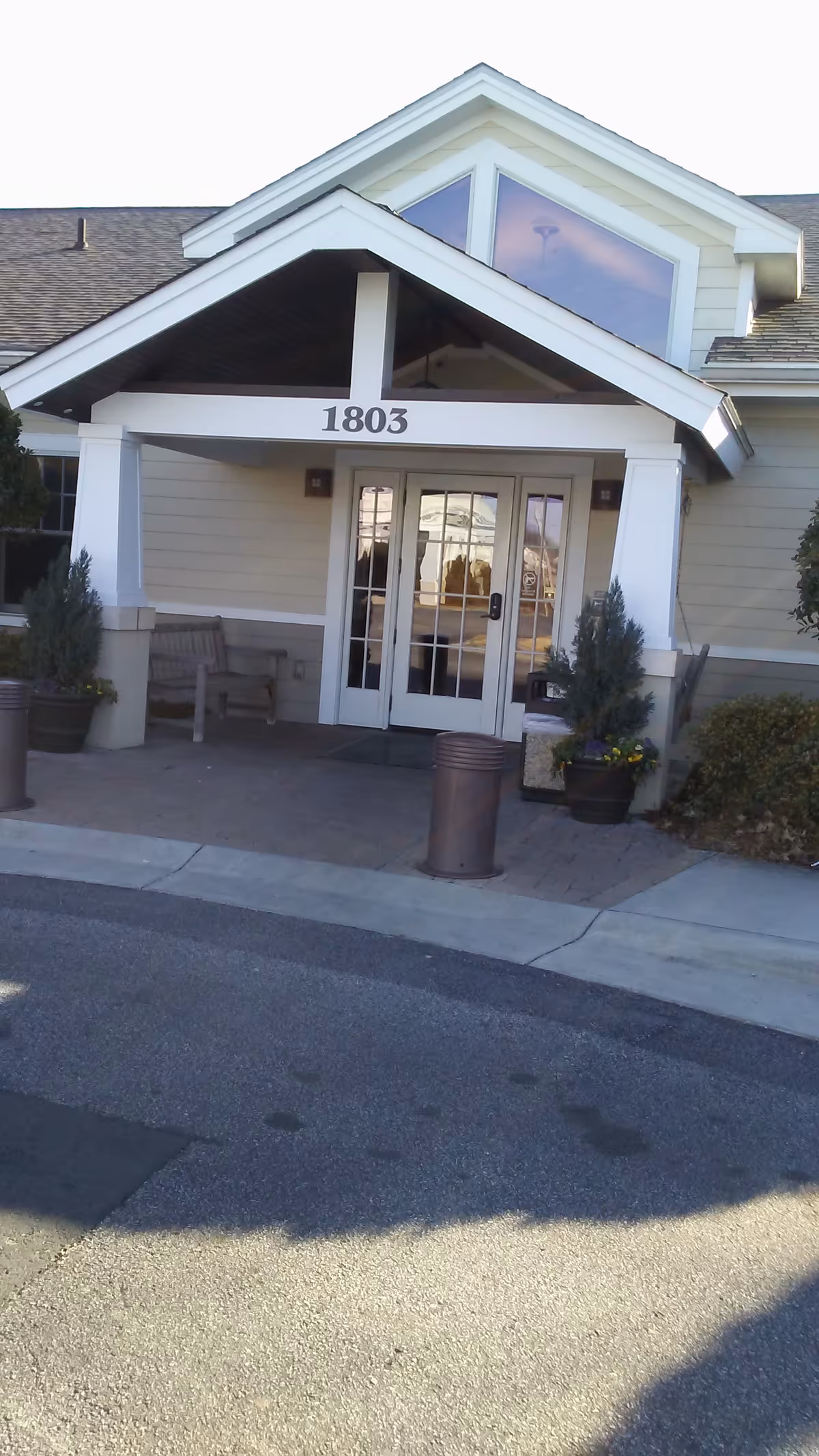 Front entrance of a beige hospice building with a peaked roof and glass doors