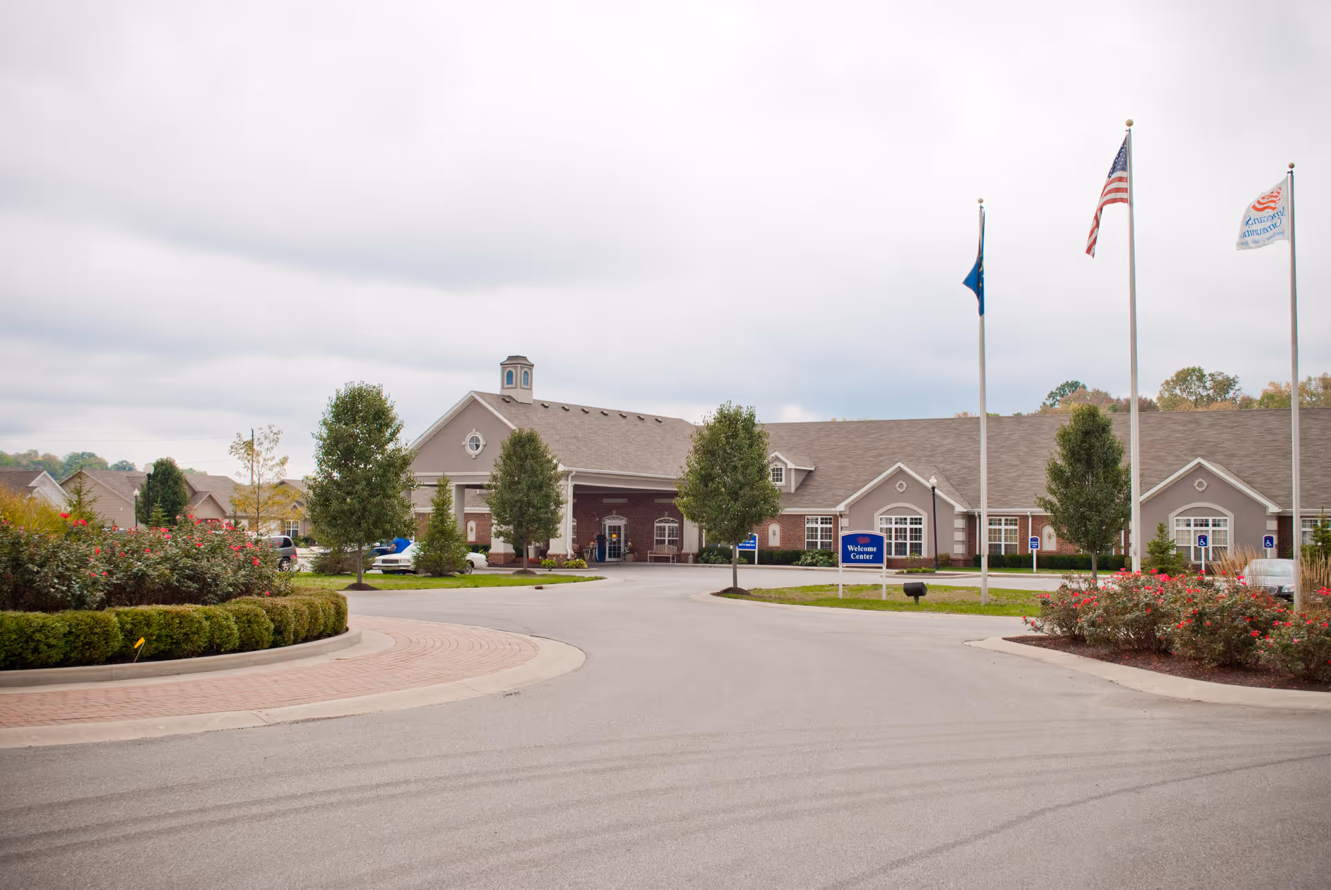 Meadow Lakes senior living facility exterior with entrance, flagpoles, and landscaped grounds.