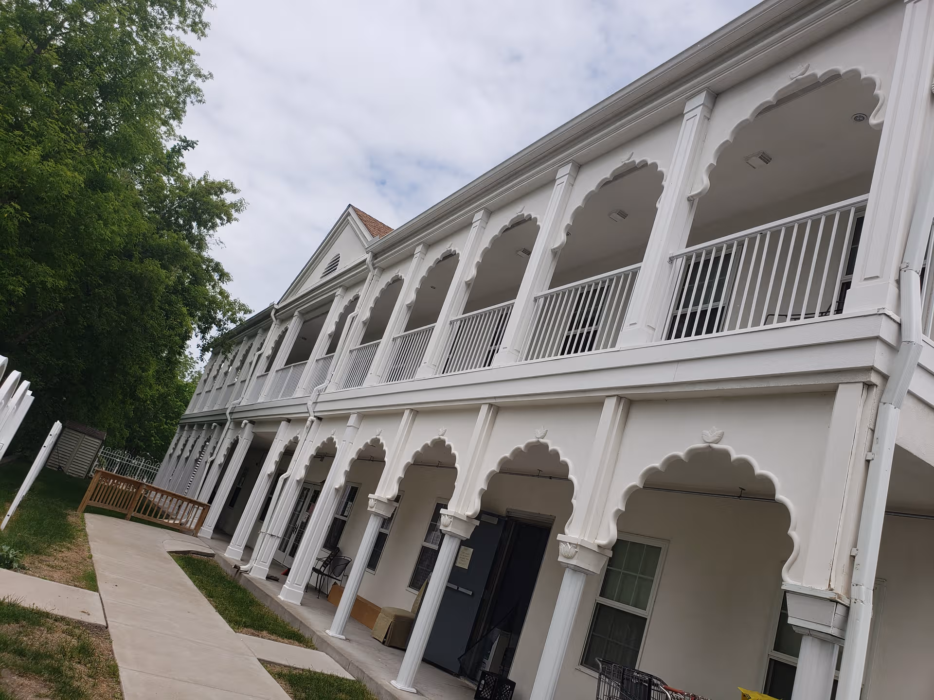White two-story building with arched balconies, columns, and a walkway along the exterior.