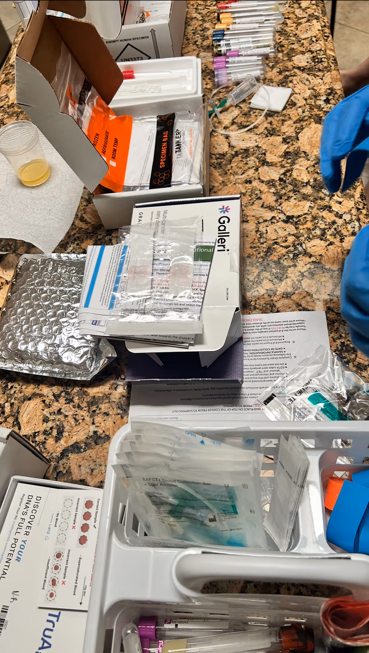 Medical supplies and syringes spread across a granite counter in a clinical setting.