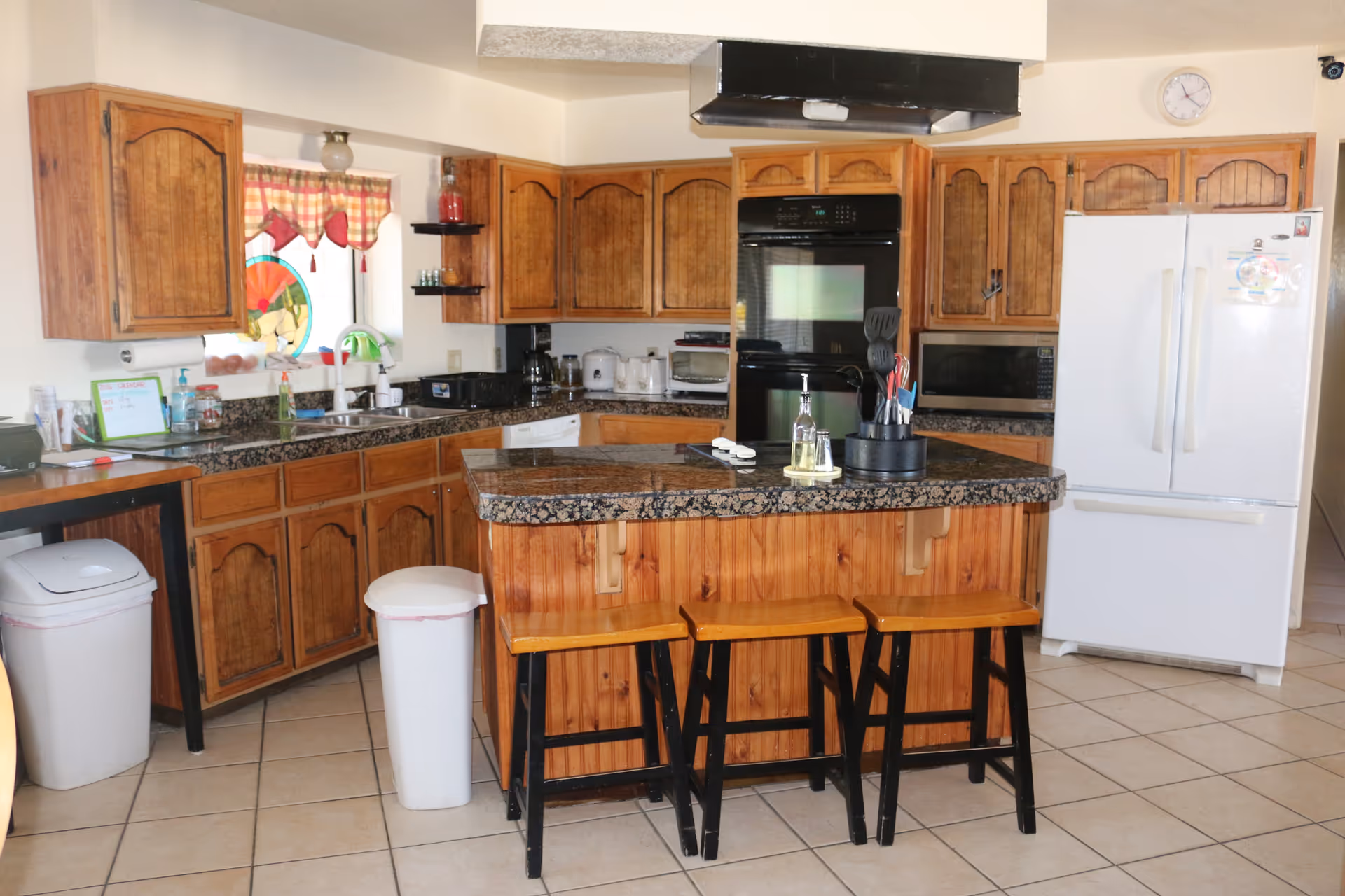 Wooden kitchen with island, stools, and white appliances in a home-style layout