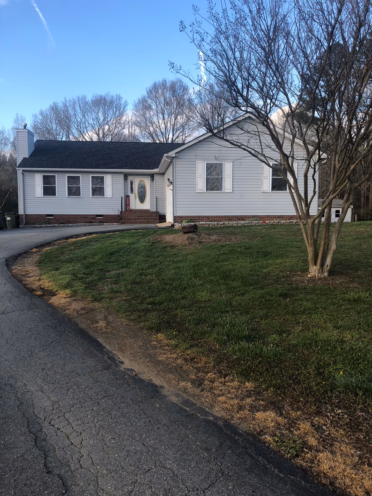 Single-story light-gray elderly care home with white trim and curved driveway.