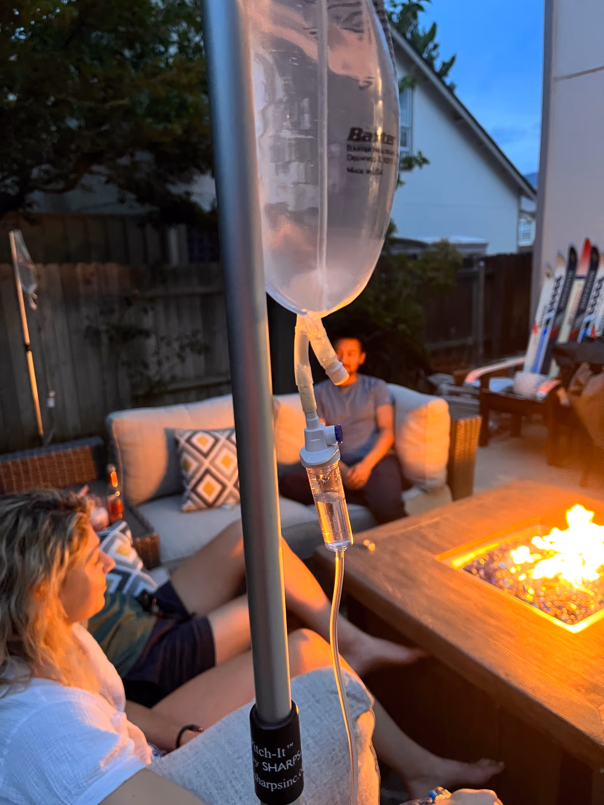 Outdoor patio with a fire pit, two residents, and an IV drip nearby.