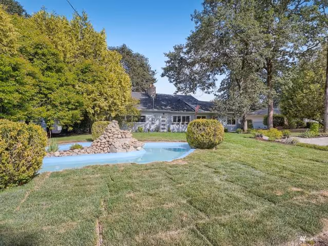 Front view of West Bliss Adult Family Home LLC with green lawn and water feature.