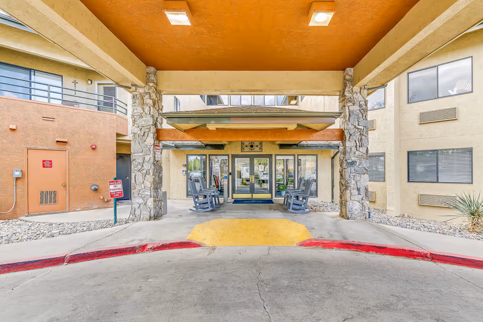 Covered entrance to Solstice Senior Living at Mesa View with stone pillars and outdoor seating.