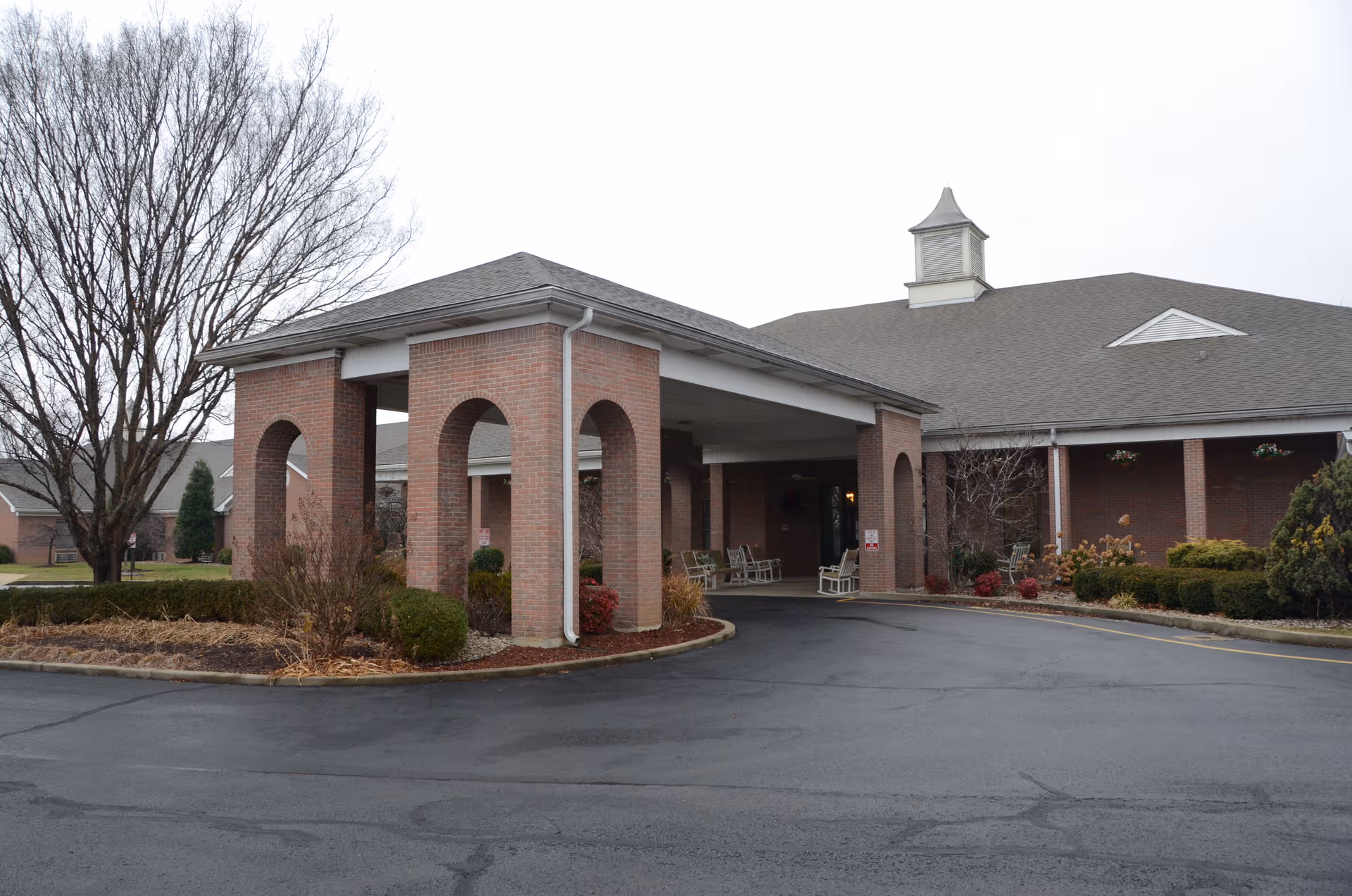 Brick senior living facility entrance with a covered drive-through and arched entry.