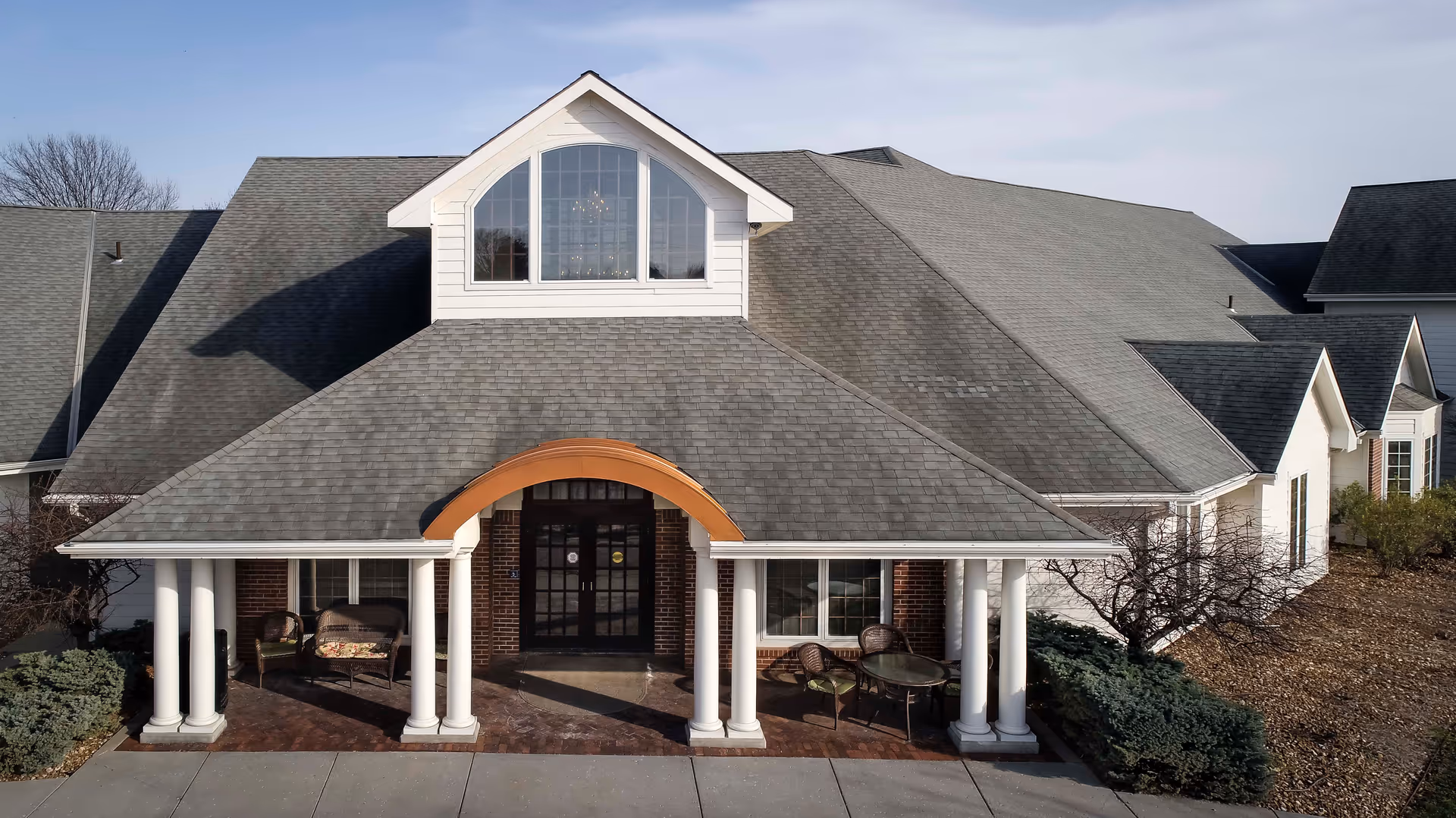 Exterior view of Pioneer Ridge Assisted Living facility with arched entrance and front porch.
