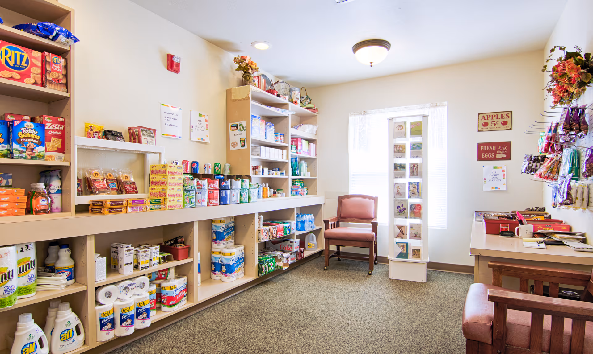Interior in-facility store with shelves of groceries, supplies, and seating.