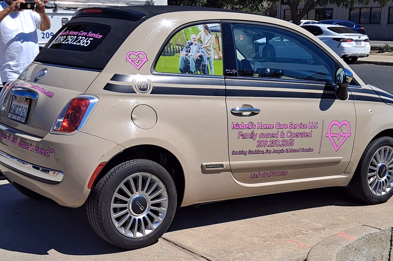 Beige van with pink heart logo and Isiabell's Home Care branding parked.