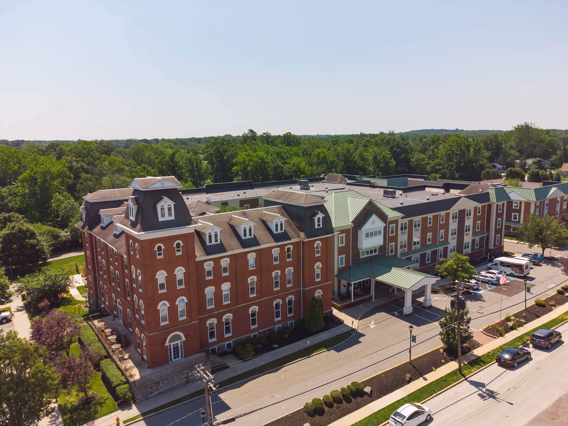 Aerial view of the brick Woodbury Mews building with green roofs, a covered entrance, parking lot and surrounding trees.