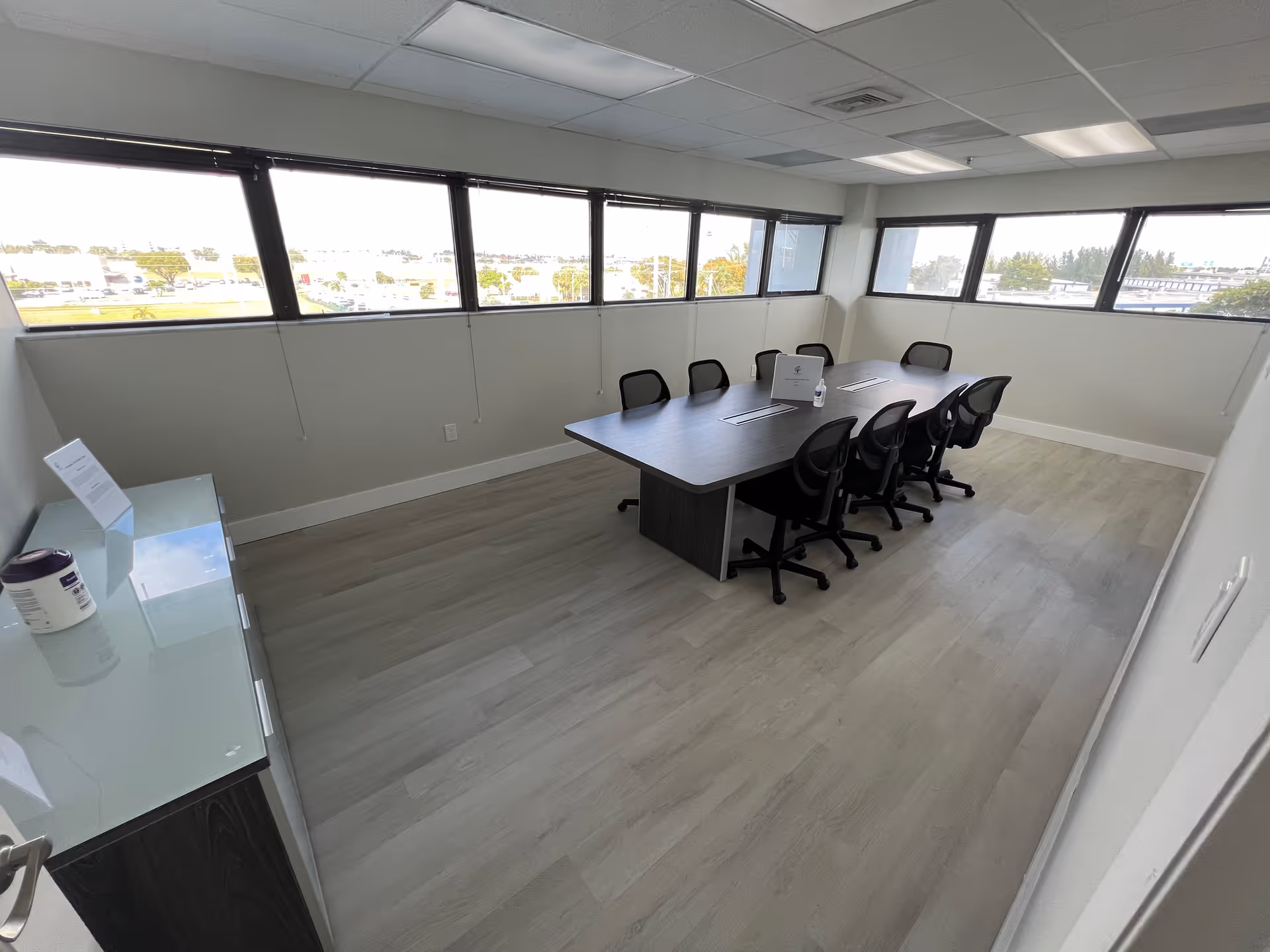 Bright interior conference room with a long table, chairs, and windows along two walls.