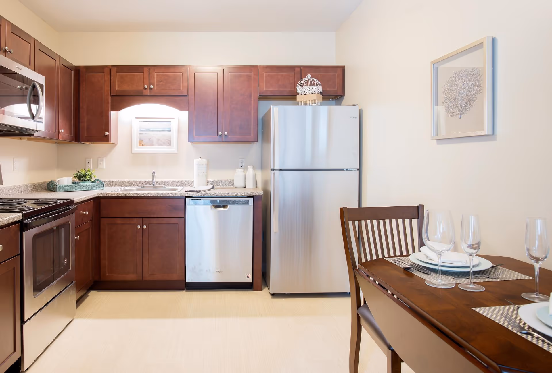 Modern kitchen with wooden cabinets, stainless appliances, and a dining table set for two.