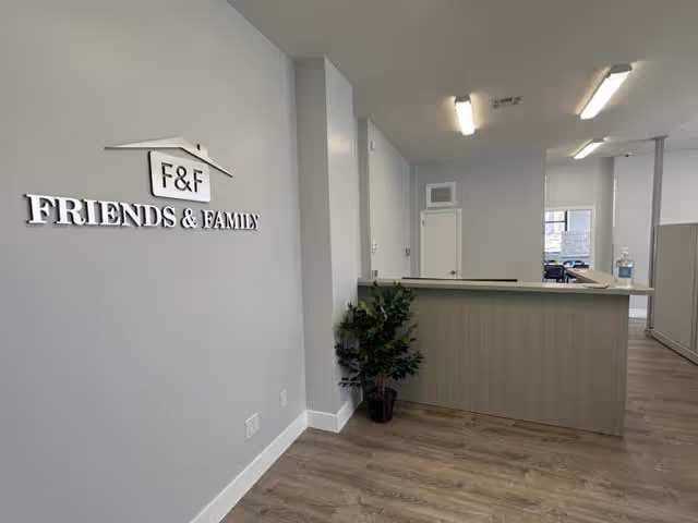 Reception area with a curved front desk and a Friends & Family sign.