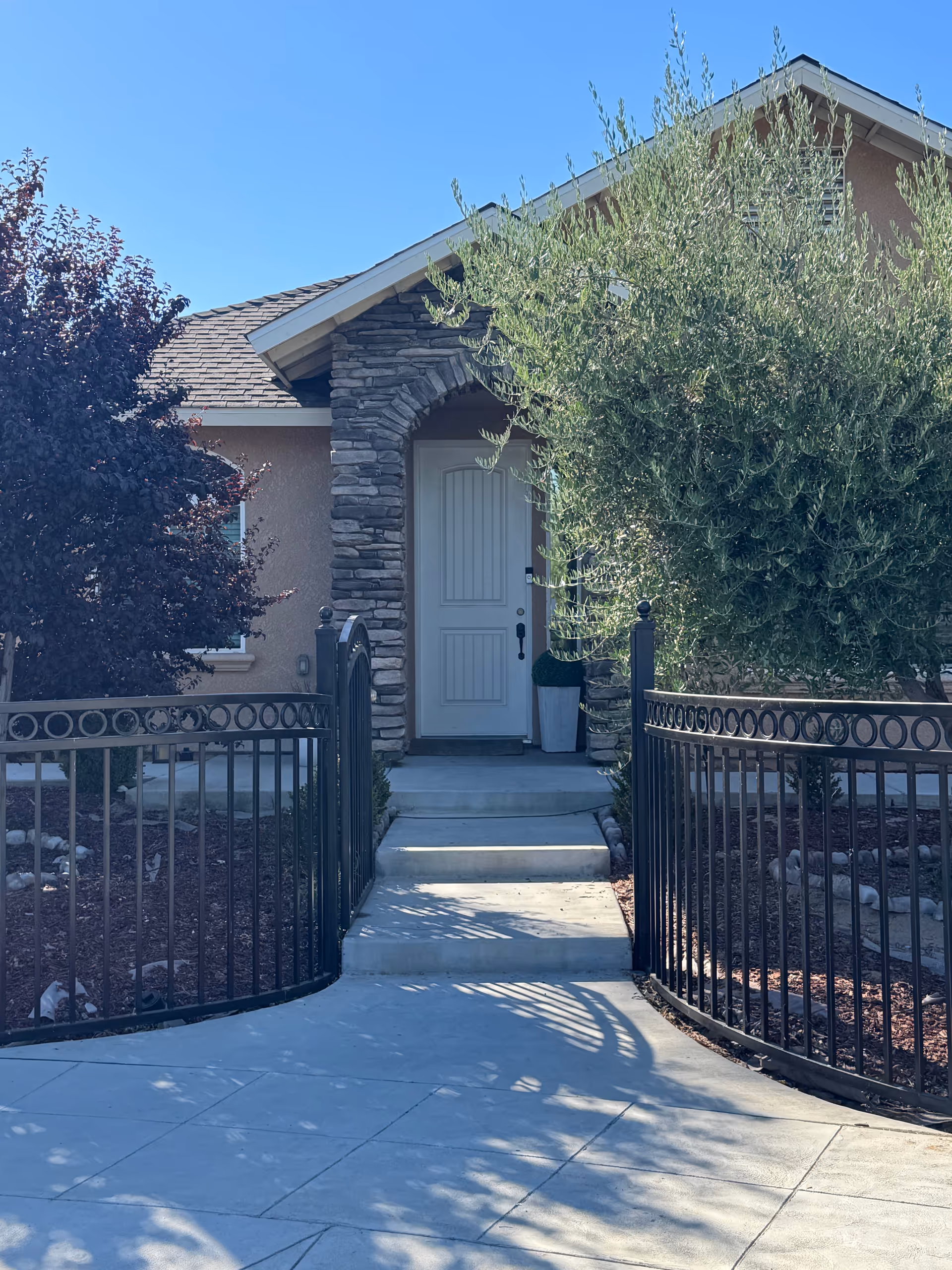 Front entrance of Ryan Lovely Assisted Living with stone arch and decorative iron fence.