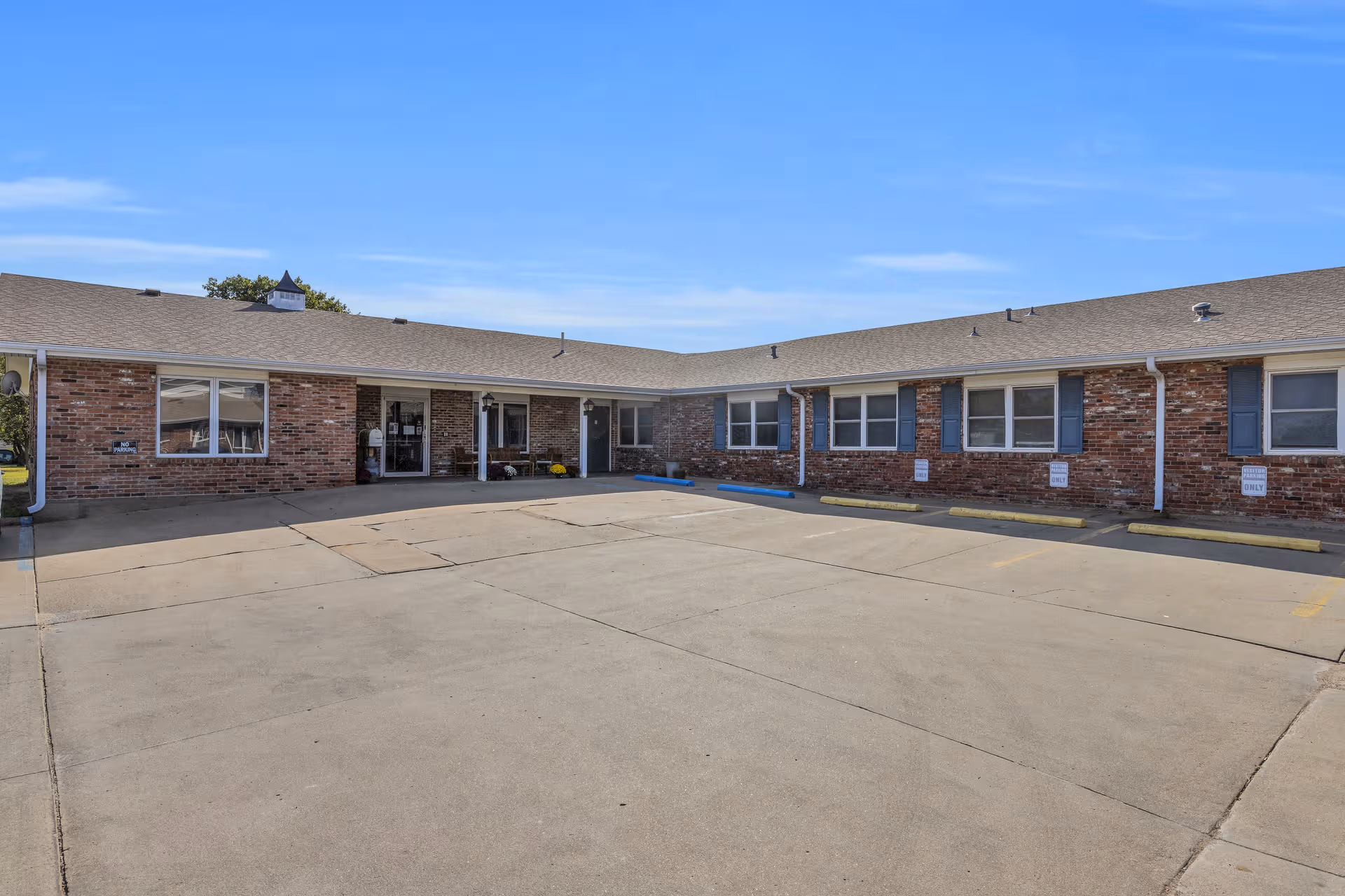Single-story brick facility with a large concrete parking lot and front entrance.