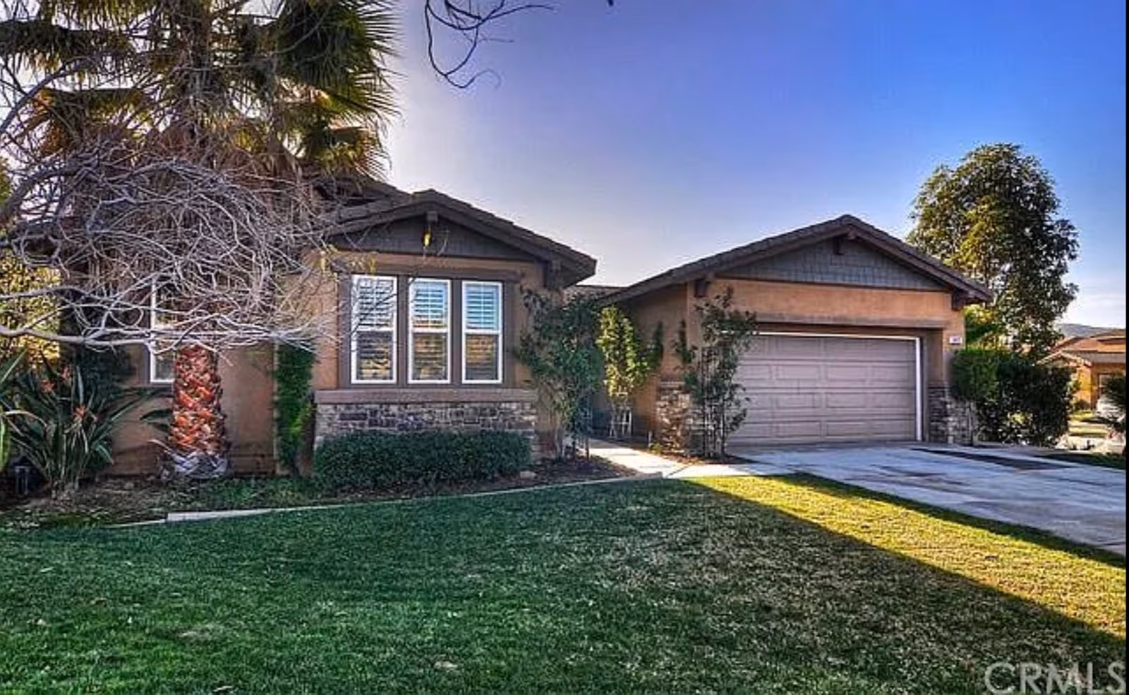 Front exterior of a suburban single-story house with a lawn and two-car garage.