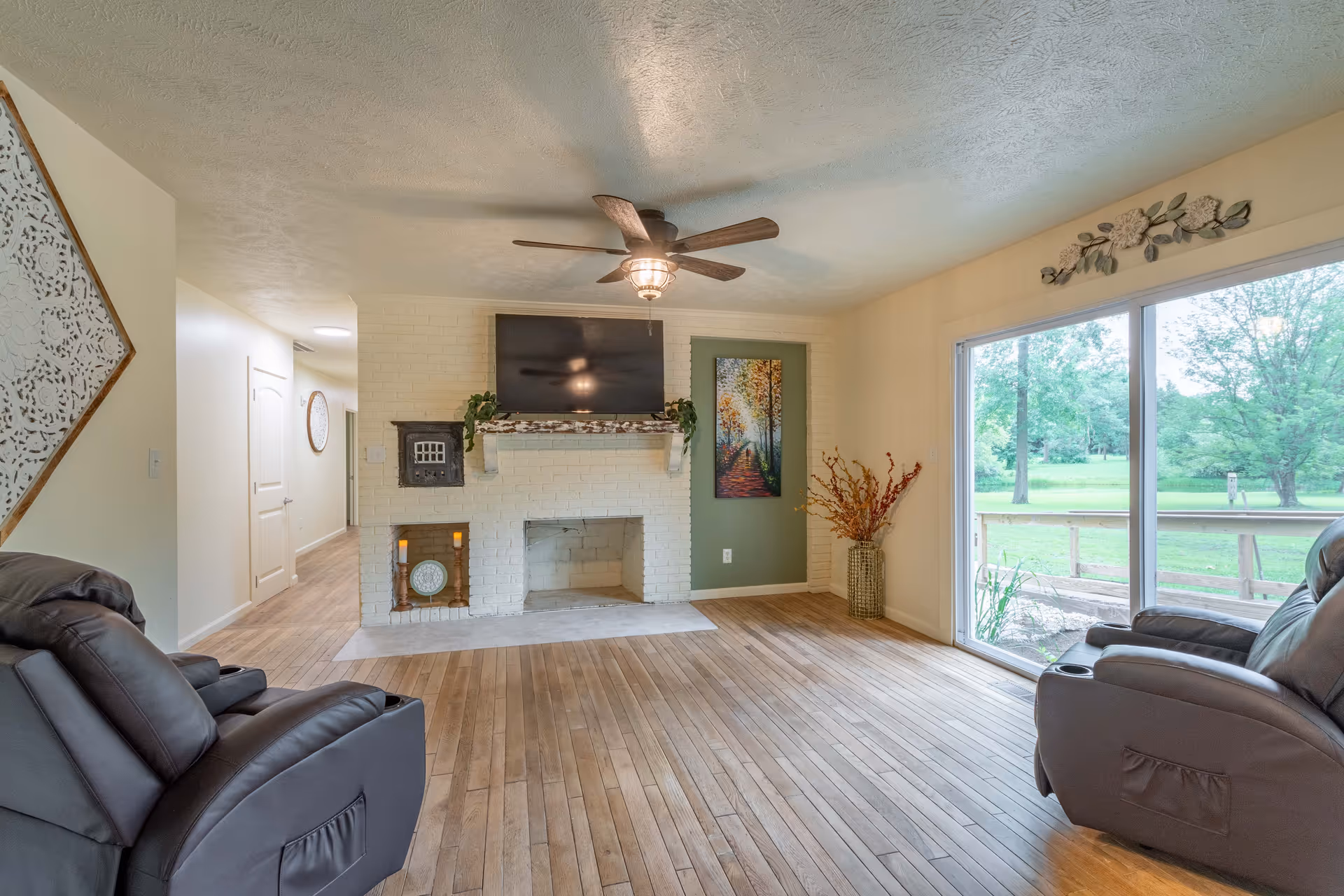 Bright living room with a white brick fireplace, mounted TV, and large sliding door.
