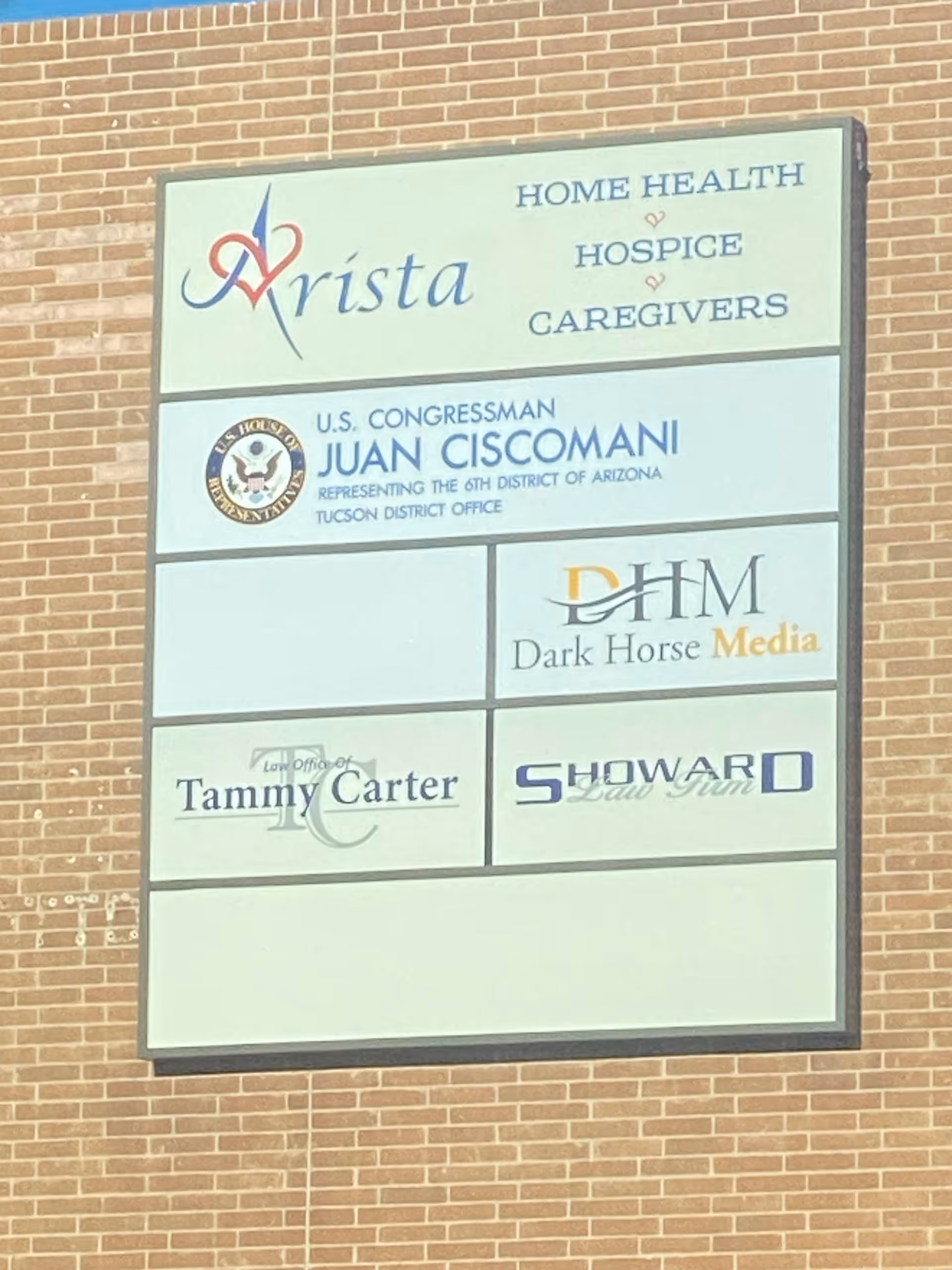 A large multi-panel sign attached to a brick exterior wall advertising Arista and affiliates.