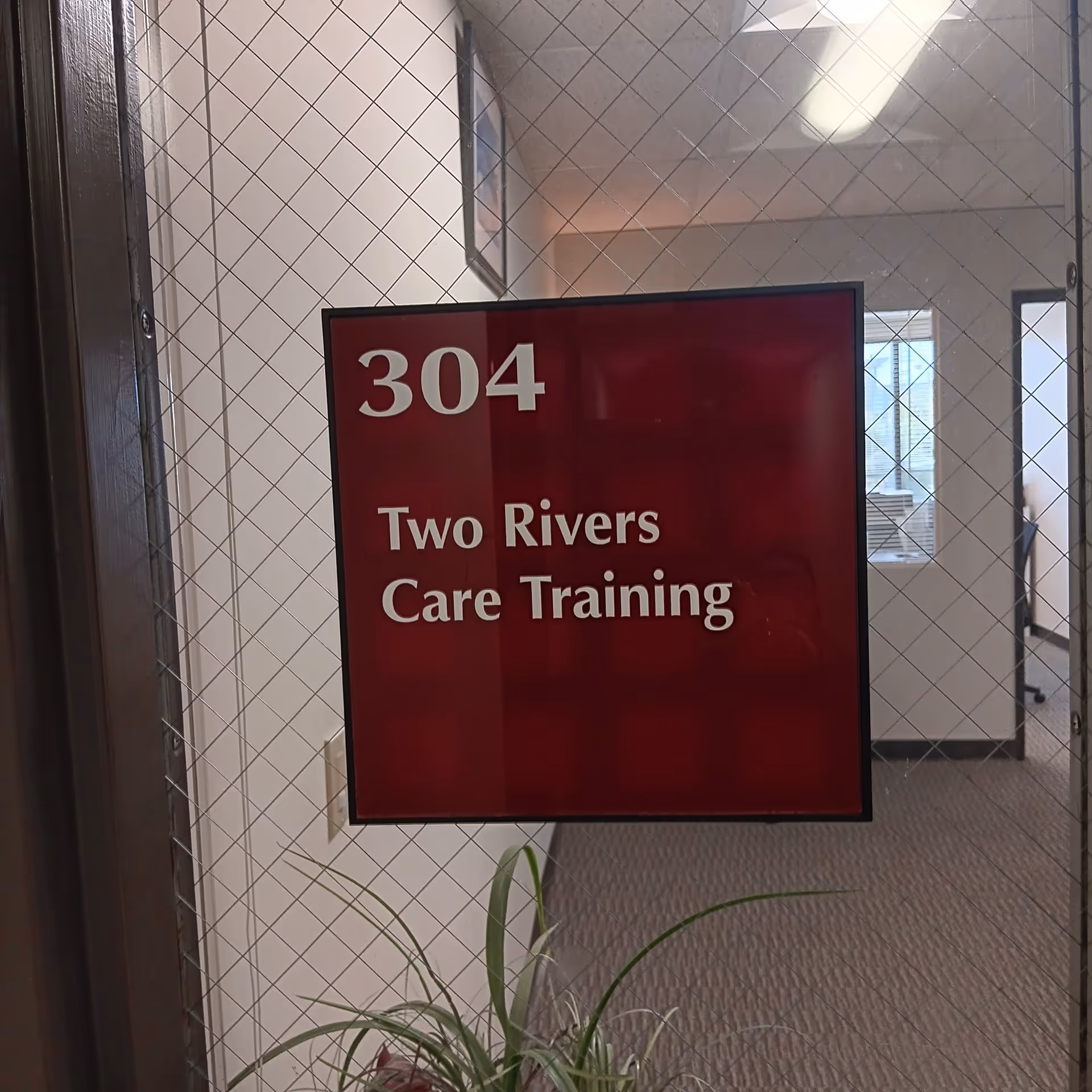 Red sign on glass door for room 304: Two Rivers Care Training.