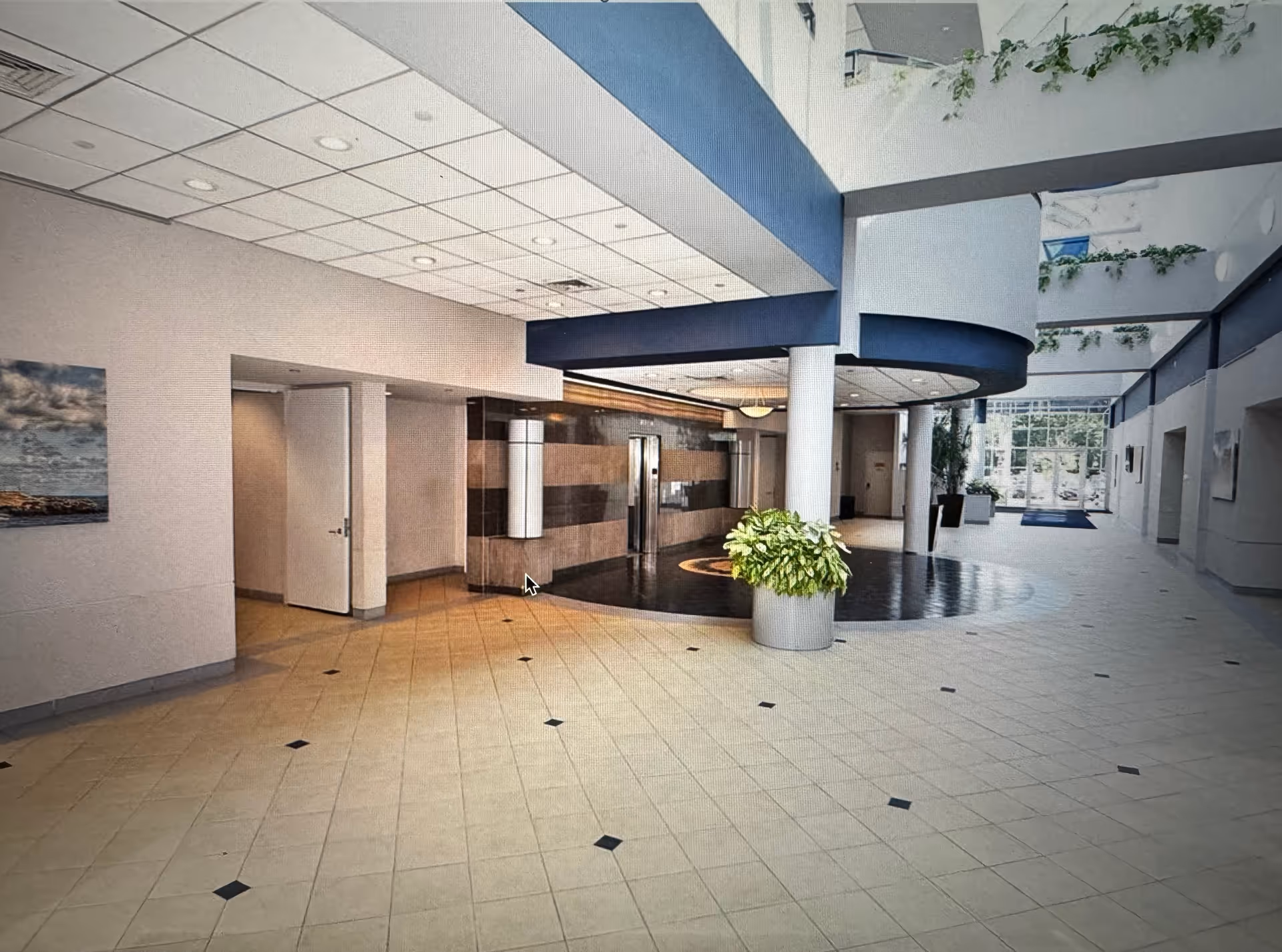 Spacious modern interior lobby with tiled floor, blue arches, and potted plants.