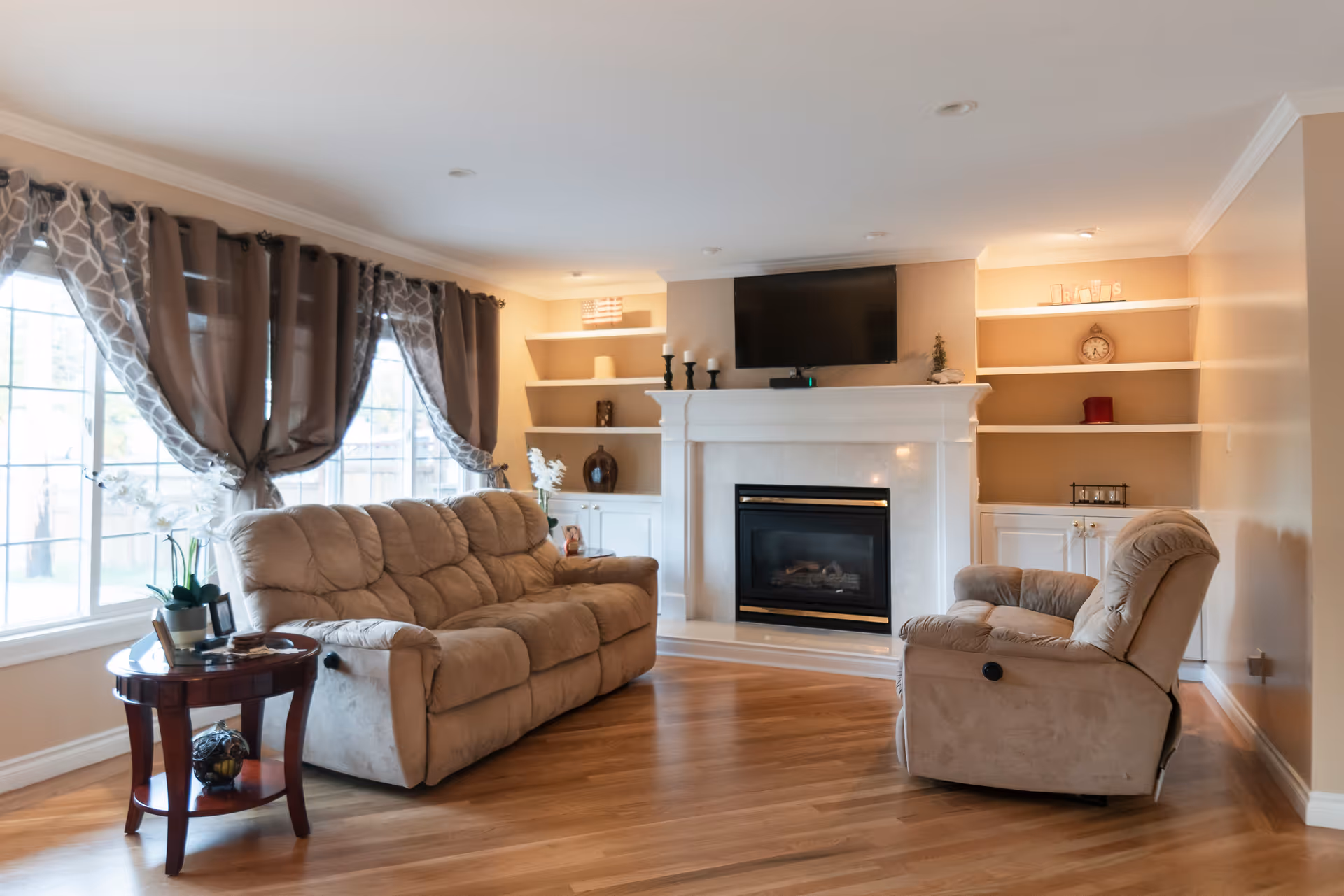 Bright living room with beige sofa, recliner, fireplace, and built-in shelves.