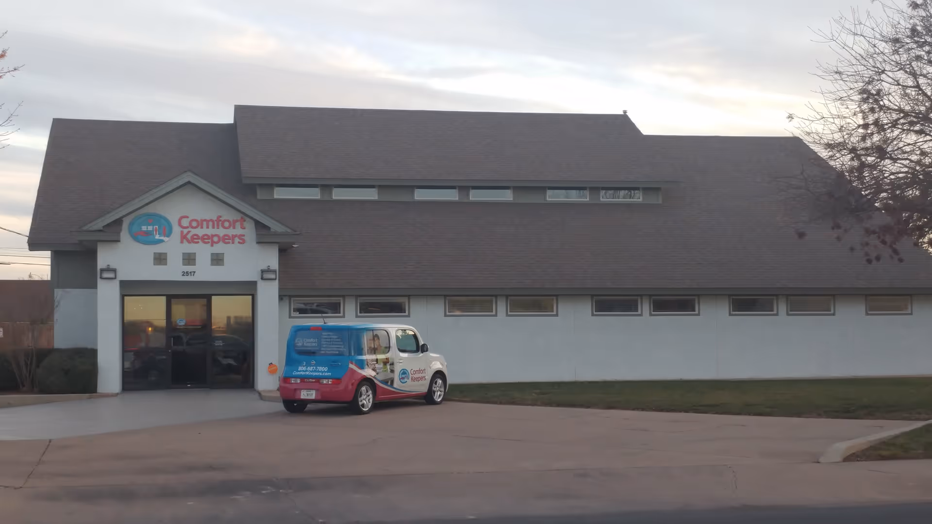 Exterior view of a Comfort Keepers building with a colorful service van parked at the entrance.