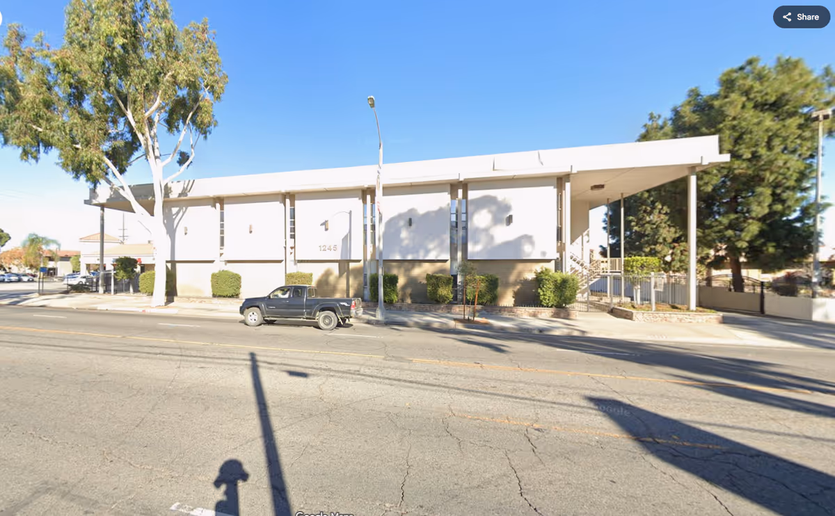 Front view of QCare Connect Inc. facility: a single-story white building with covered entrance on street
