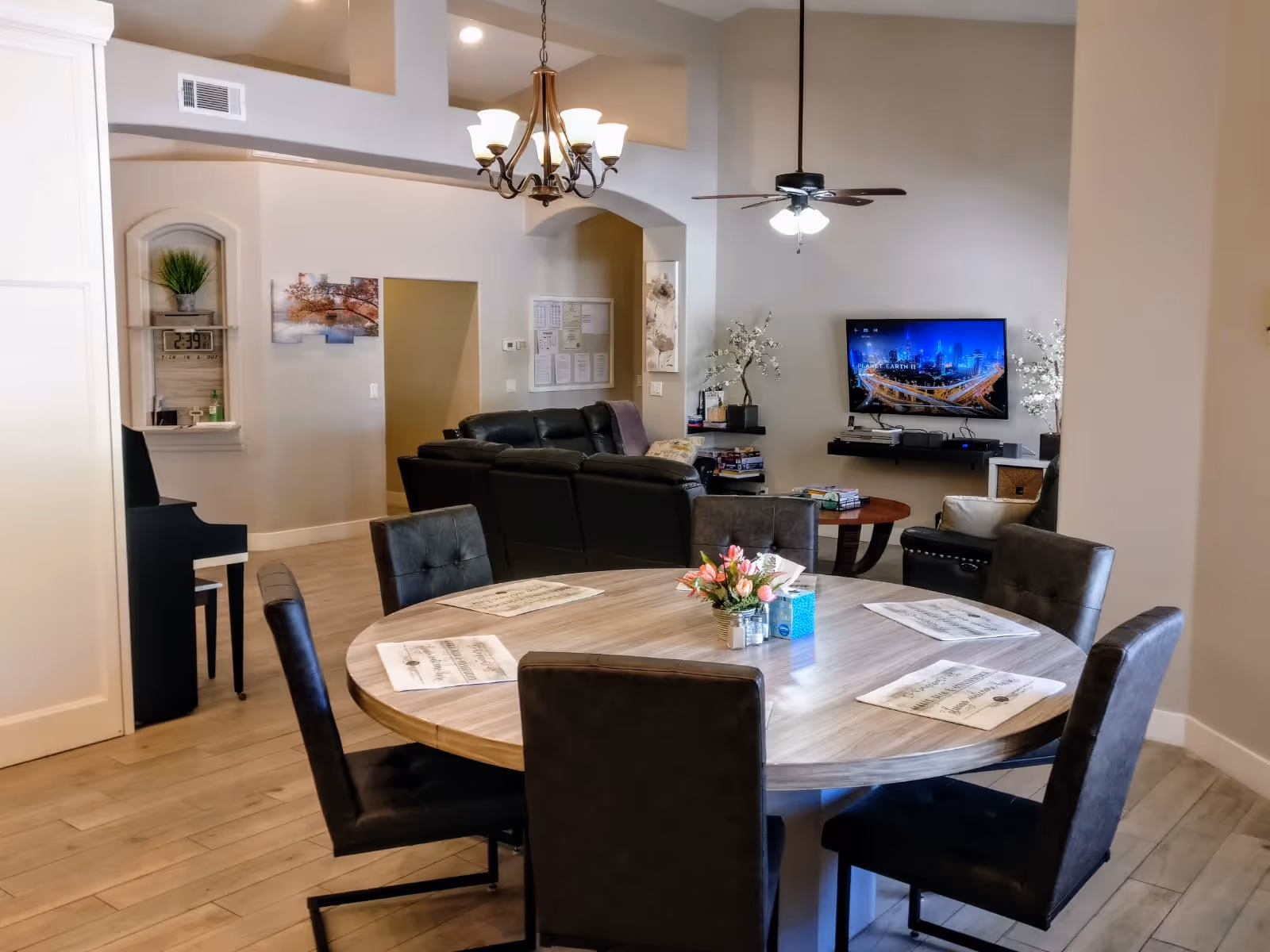Open communal dining and living area with round table and TV in the background.