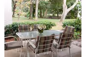 Outdoor patio with a glass table and striped cushioned chairs.