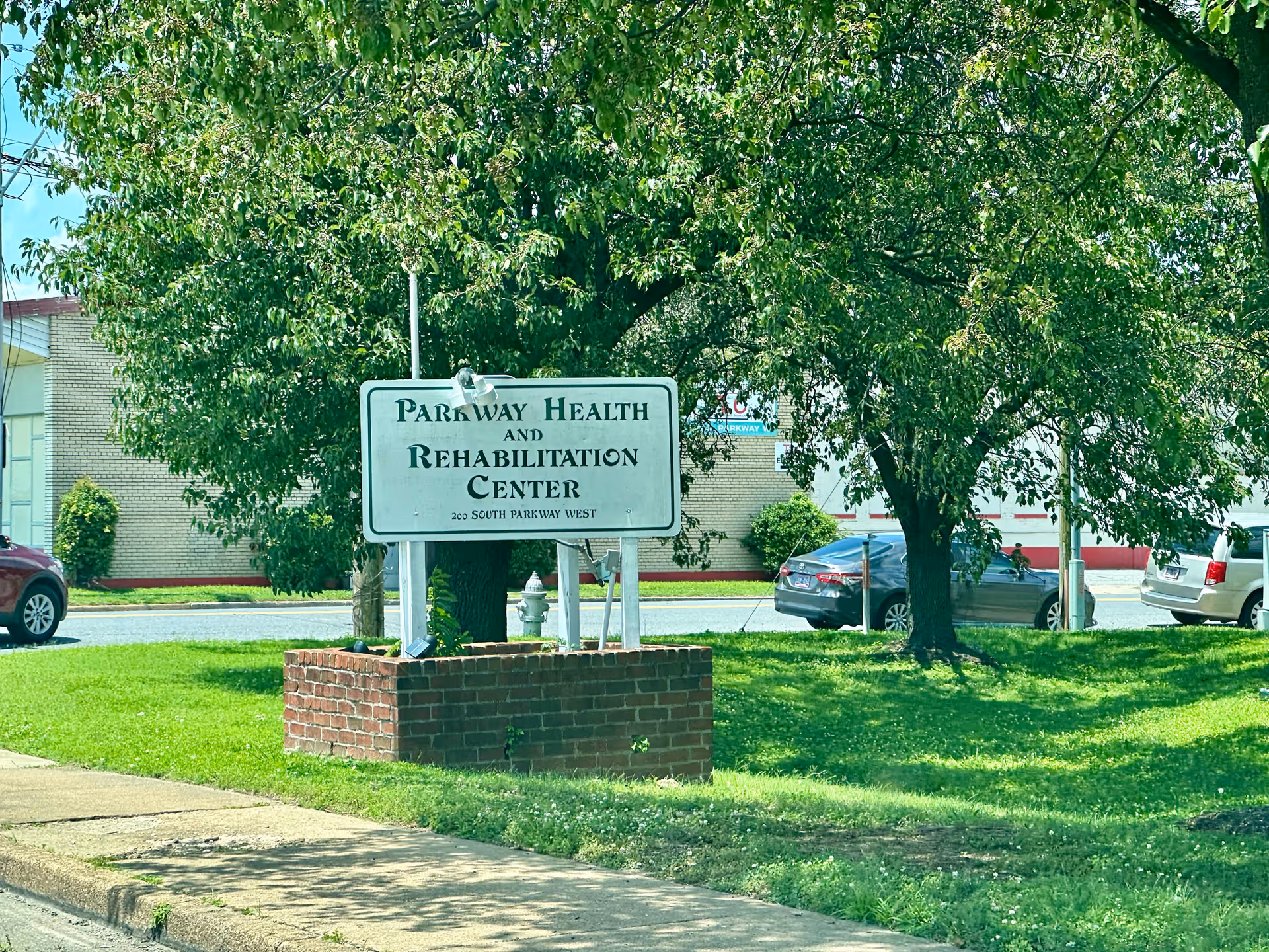 Parkway Health and Rehabilitation Center sign beside trees and a parking lot.