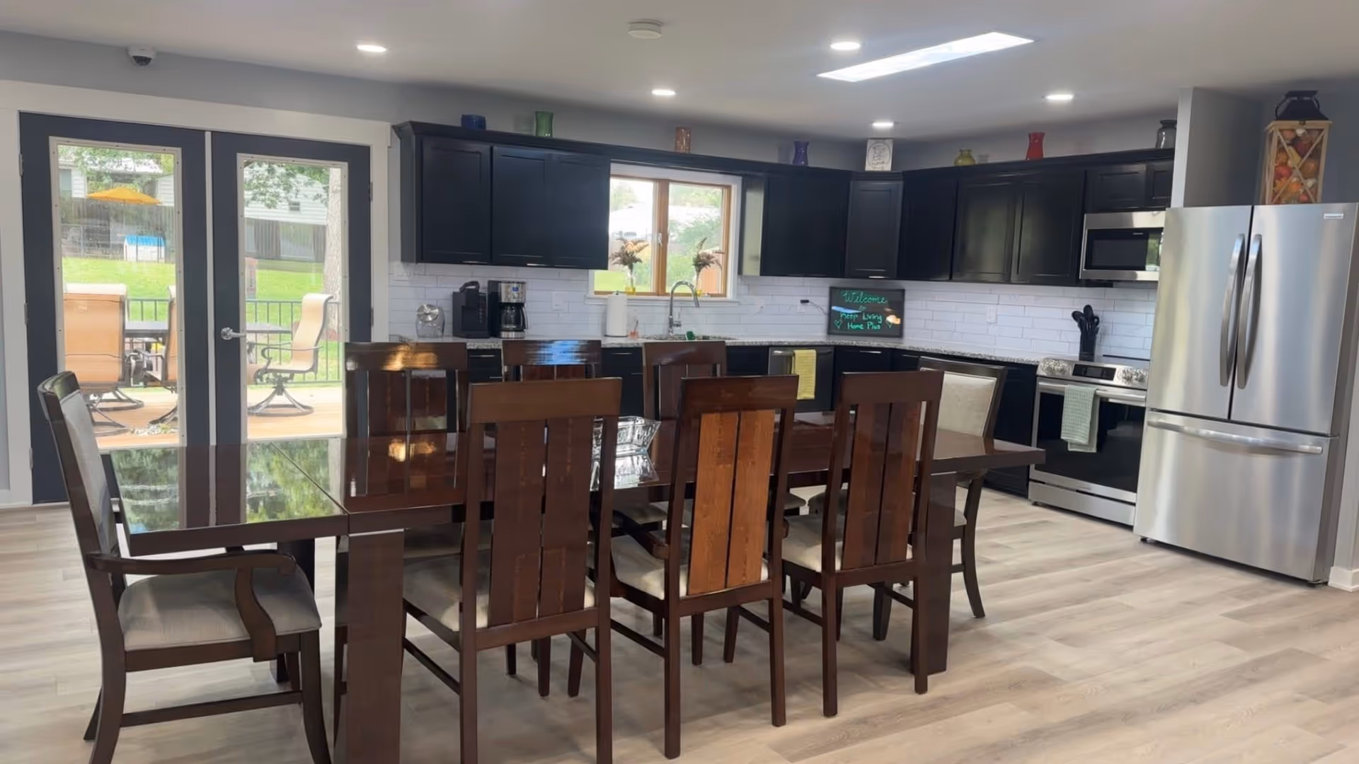 Open-concept kitchen and dining area with dark wood table and stainless steel appliances.