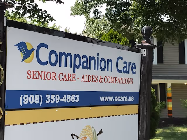 Outdoor sign reads Companion Care Senior Care with contact information beside a residential building.