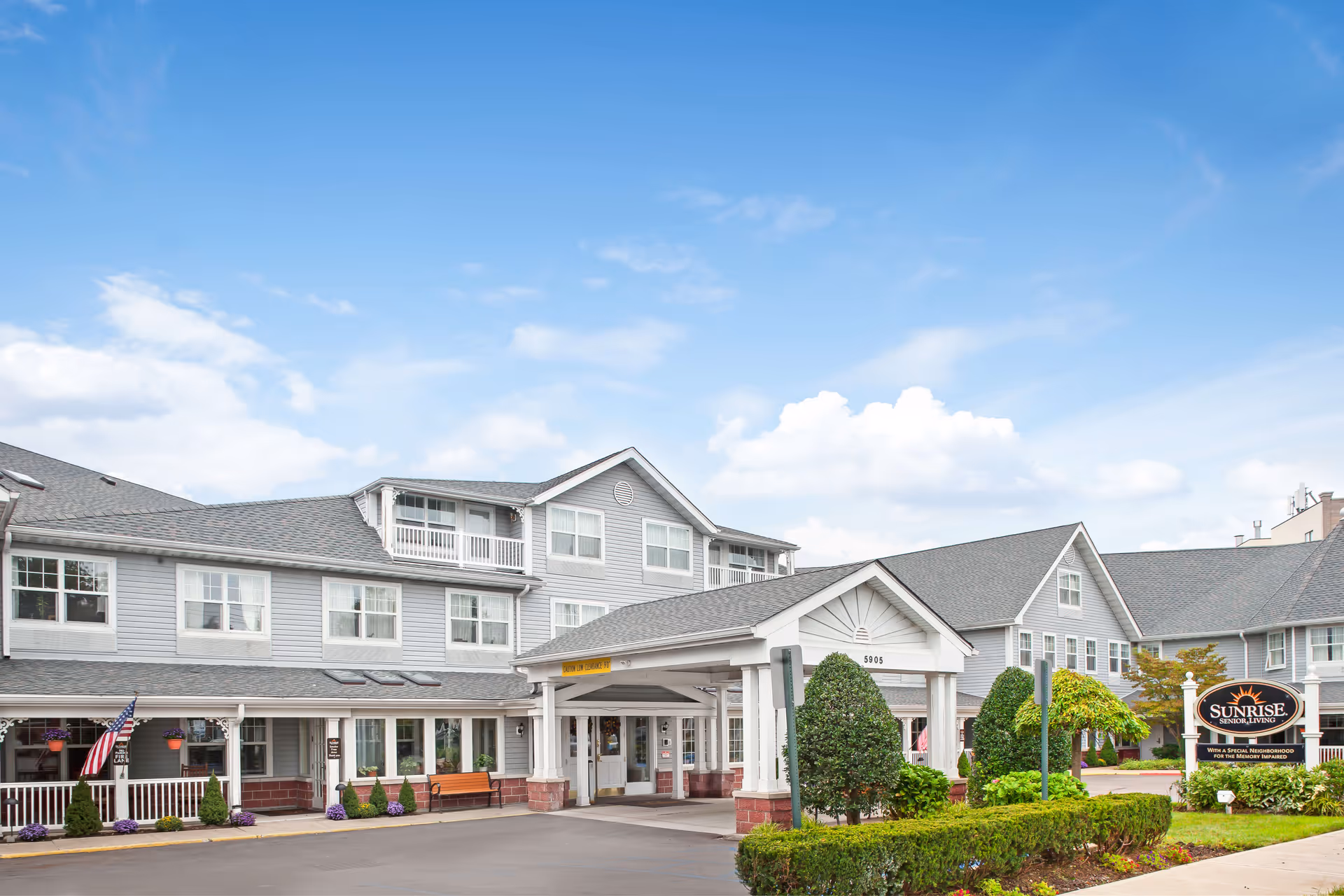 Sunrise at Mill Basin senior living facility exterior with a covered entrance and landscaped front.