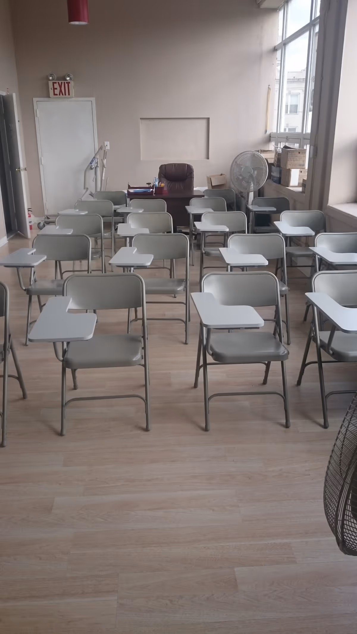 Rows of gray desks and chairs face a front desk in a classroom style training room.