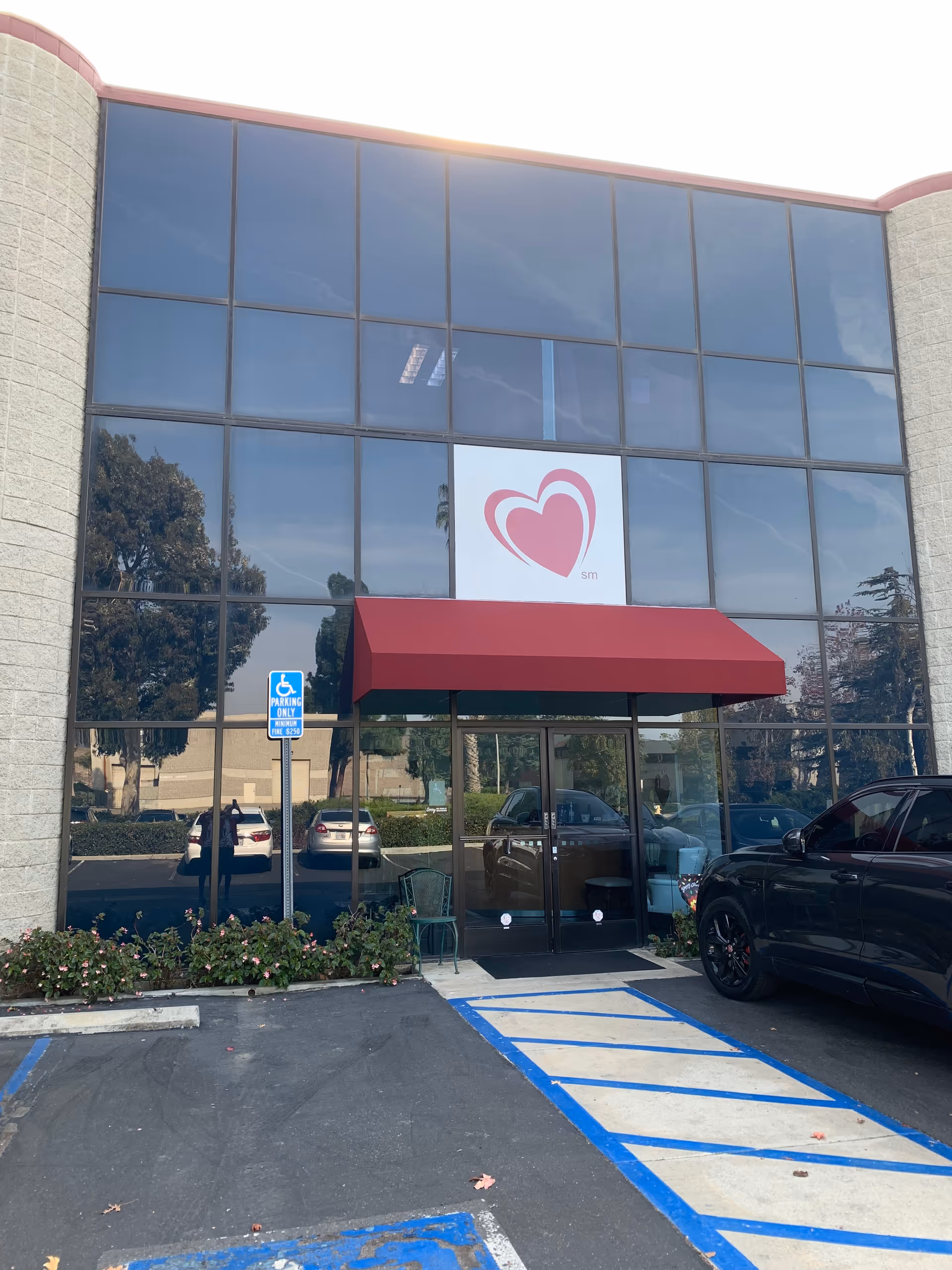 Exterior view of Access TLC facility with glass façade, red awning, and handicap parking.