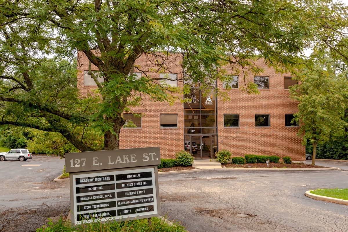 Exterior brick building with glass entry doors and a 127 E. Lake St sign.