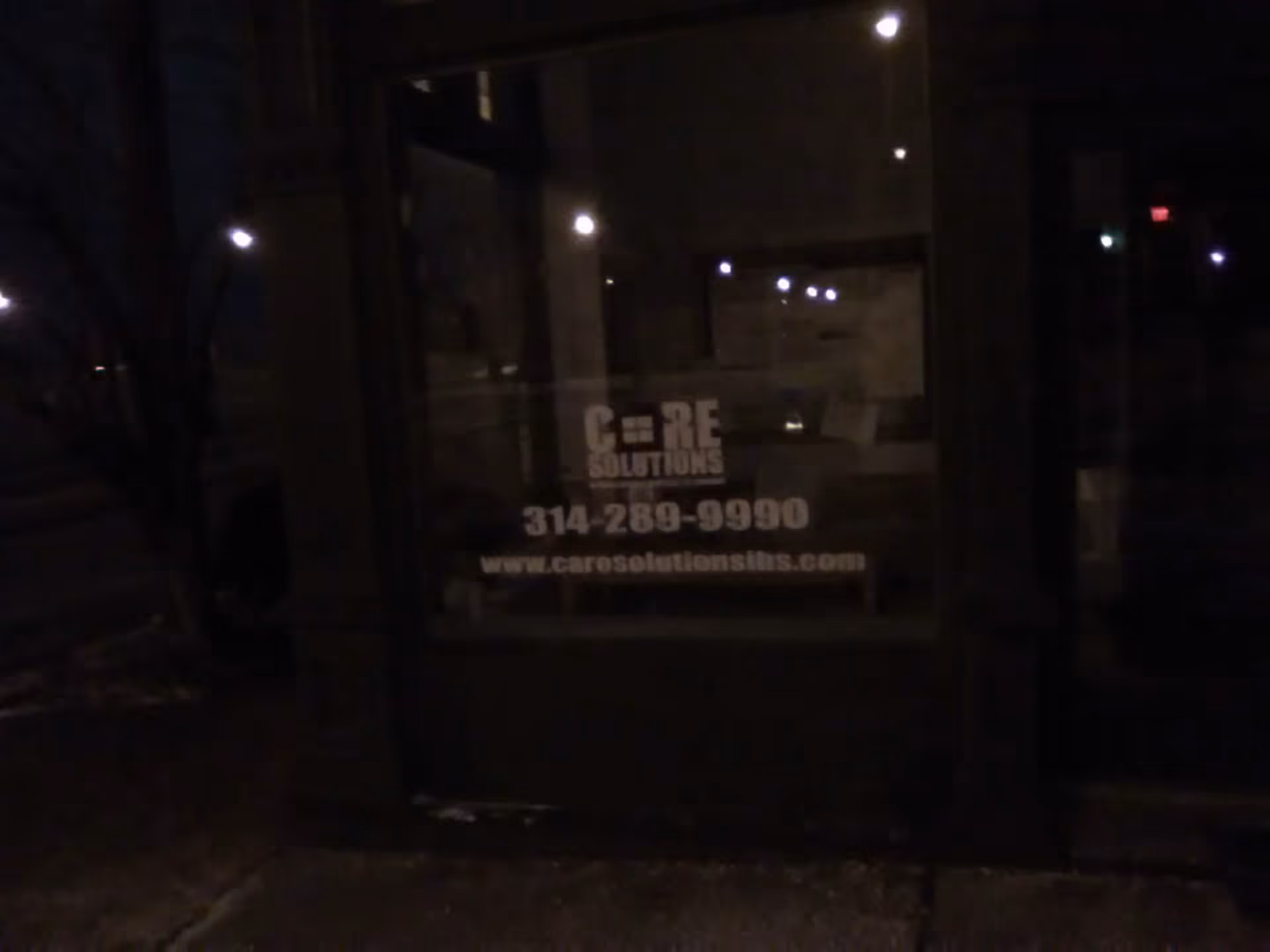 Nighttime exterior with a storefront window sign for Care Solutions In-Home Services LLC.