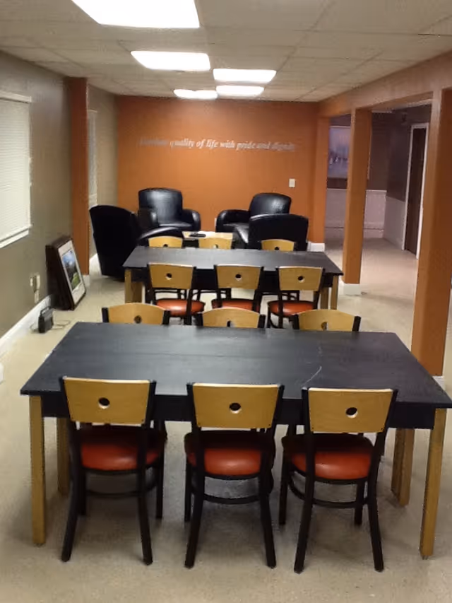 A dining room with several tables and chairs in a senior living facility.