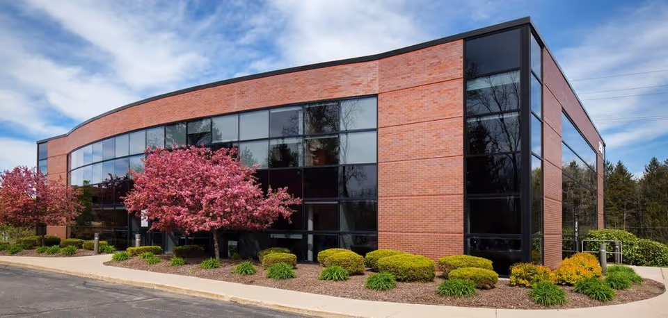 Modern brick senior living center with curved glass facade and landscaped front.